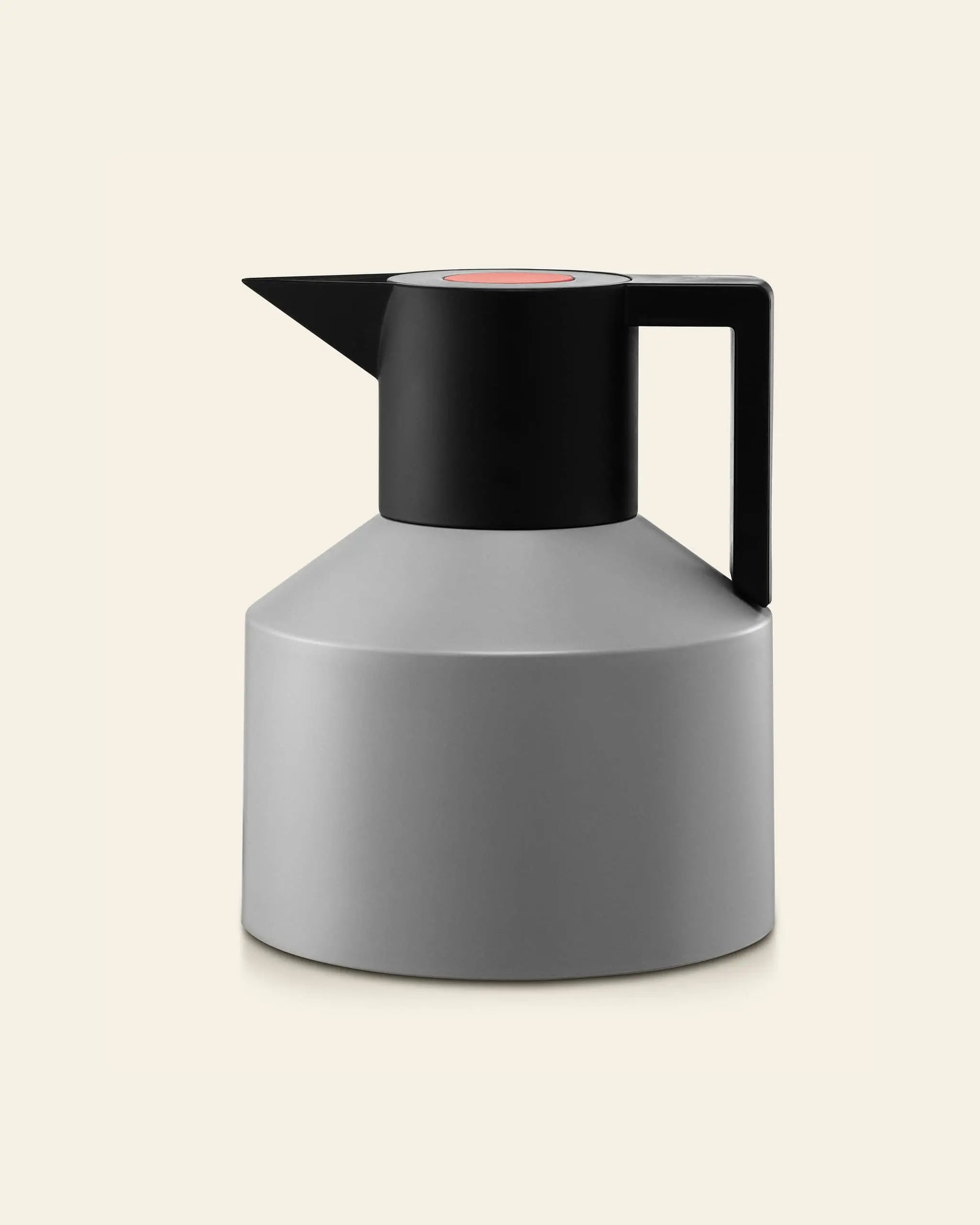 The Normann Copenhagen Geo Vacuum Jug is a matte gray and black, vacuum-insulated jug with a minimalist geometric design—cylindrical shape, flat base, rectangular handle, and short spout—by Normann Copenhagen, shown on a light beige background.