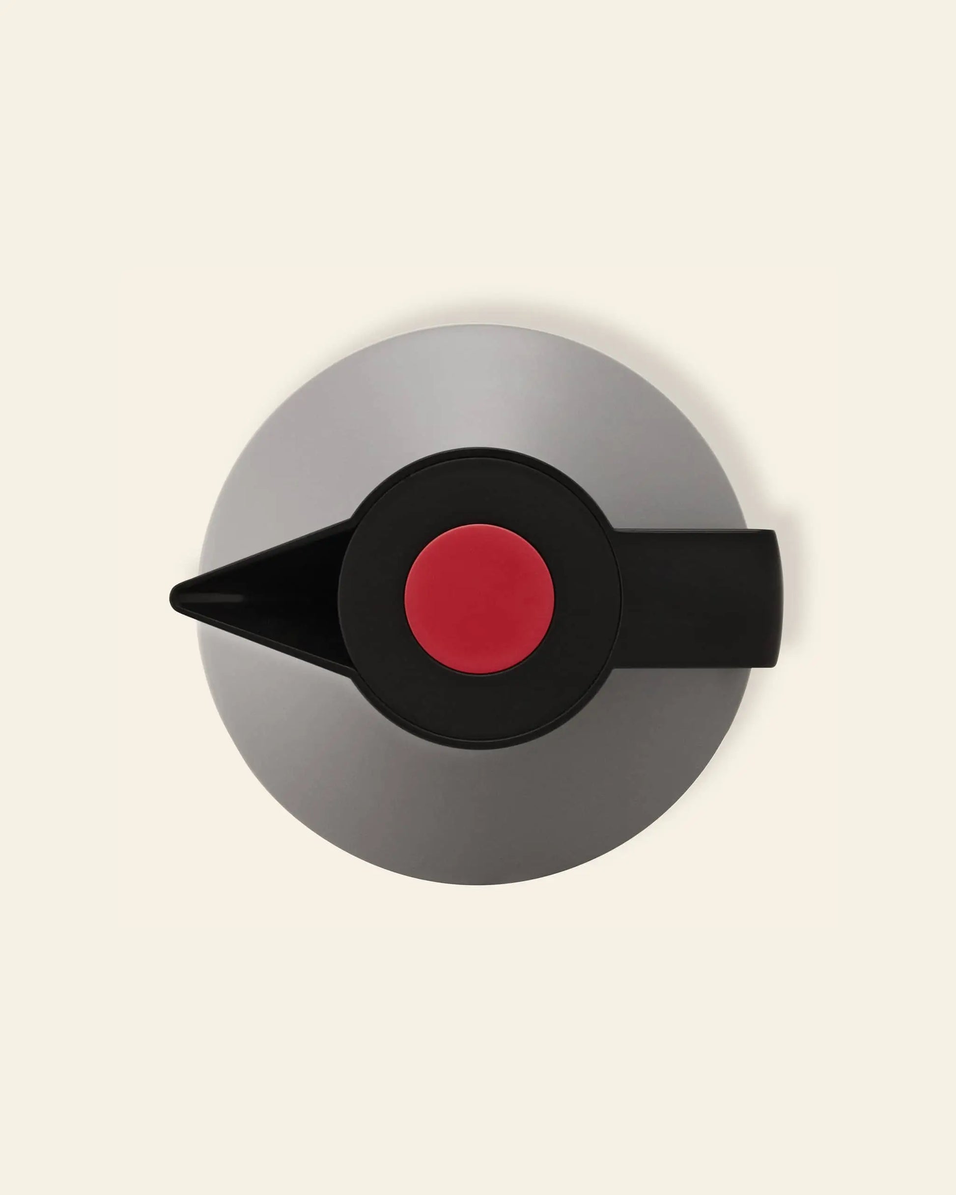 A top-down view of the Normann Copenhagen Geo Vacuum Jug, a modern round gray teapot with a black spout and handle, a large red knob on the lid, and a vacuum-insulated body, set against an off-white background.