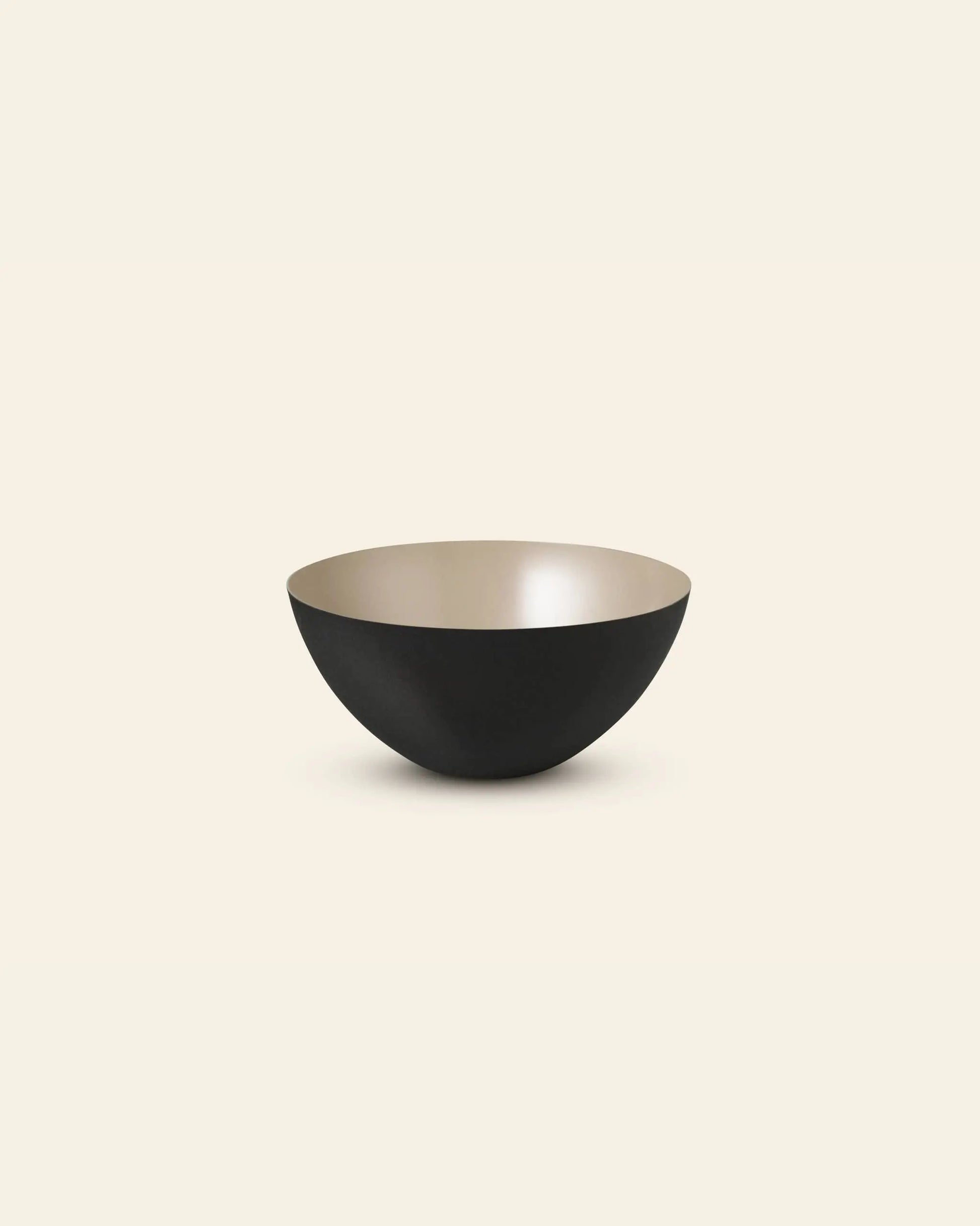 The Normann Copenhagen Krenit Bowl (12.5cm) features a minimalist, Danish-inspired round shape with a matte black exterior and smooth light beige interior, set against a plain off-white background.