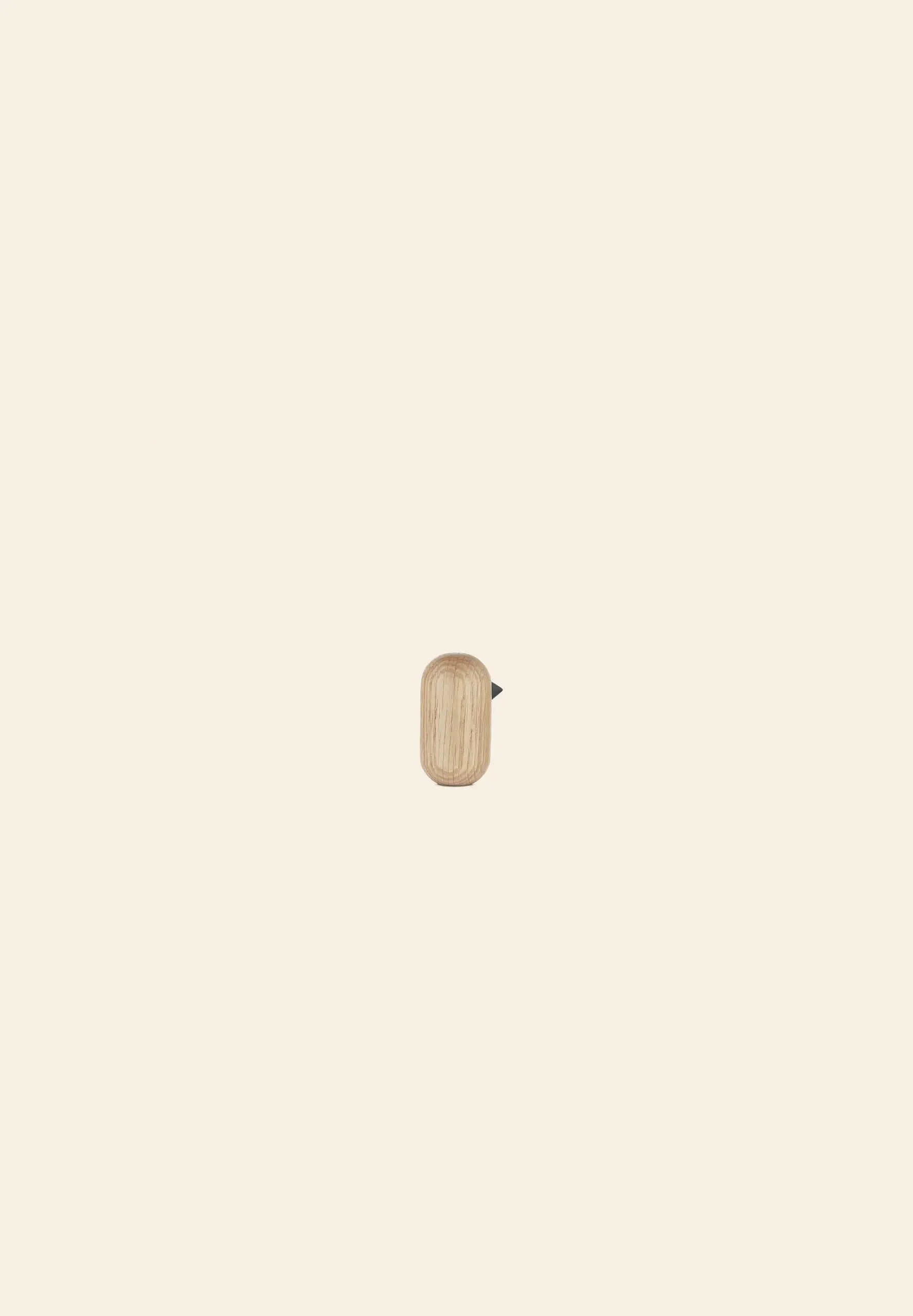 The Normann Copenhagen Little Bird, 7cm, by Normann Copenhagen is a small, rectangular wooden decor piece with rounded edges and a metal tab on the right, shown centered on a light beige background—ideal for minimalist spaces.