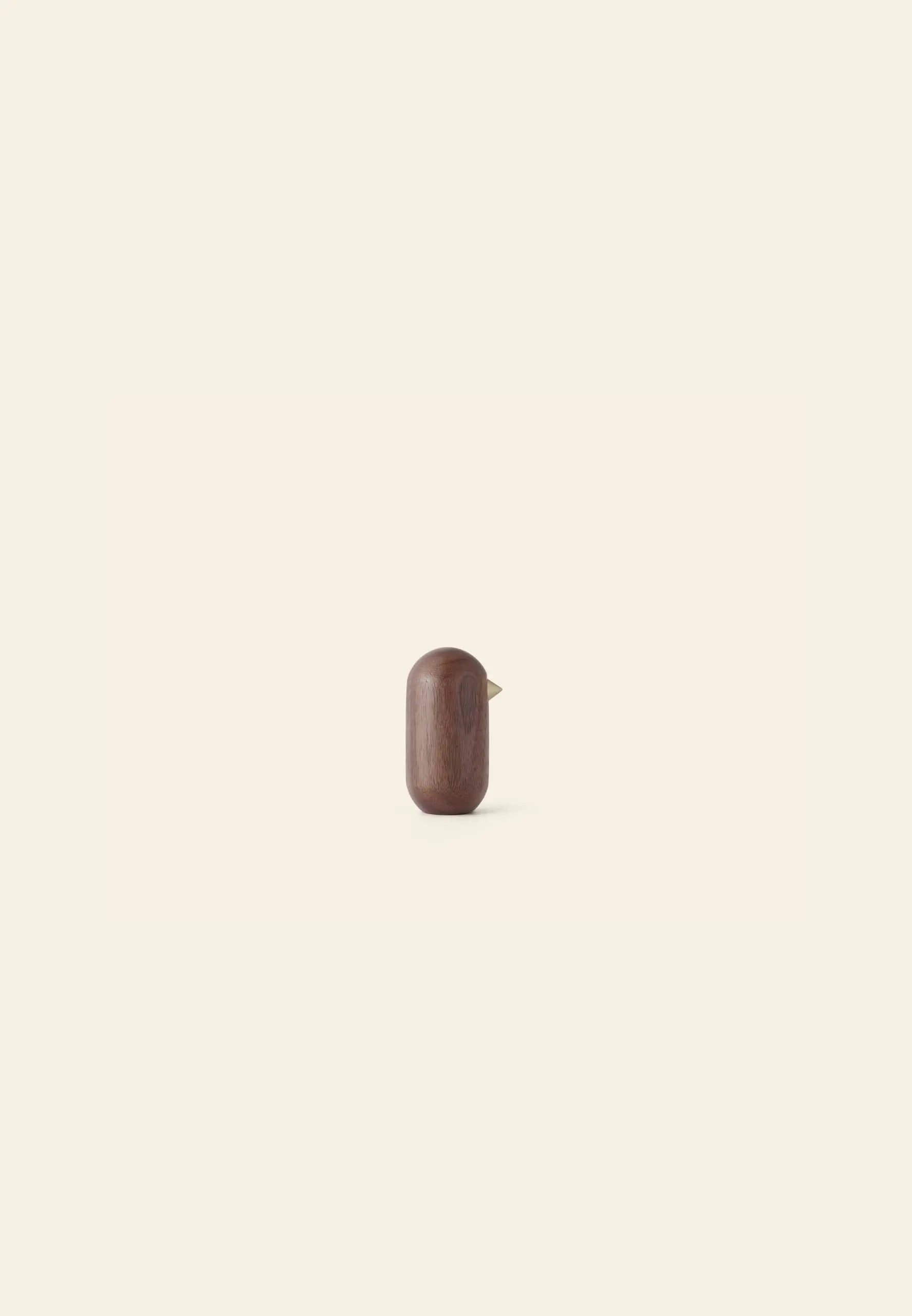 The Normann Copenhagen Little Bird, 7cm, by Normann Copenhagen features a smooth wooden body and tiny beak, bringing minimalist charm to your decor against a light beige background.