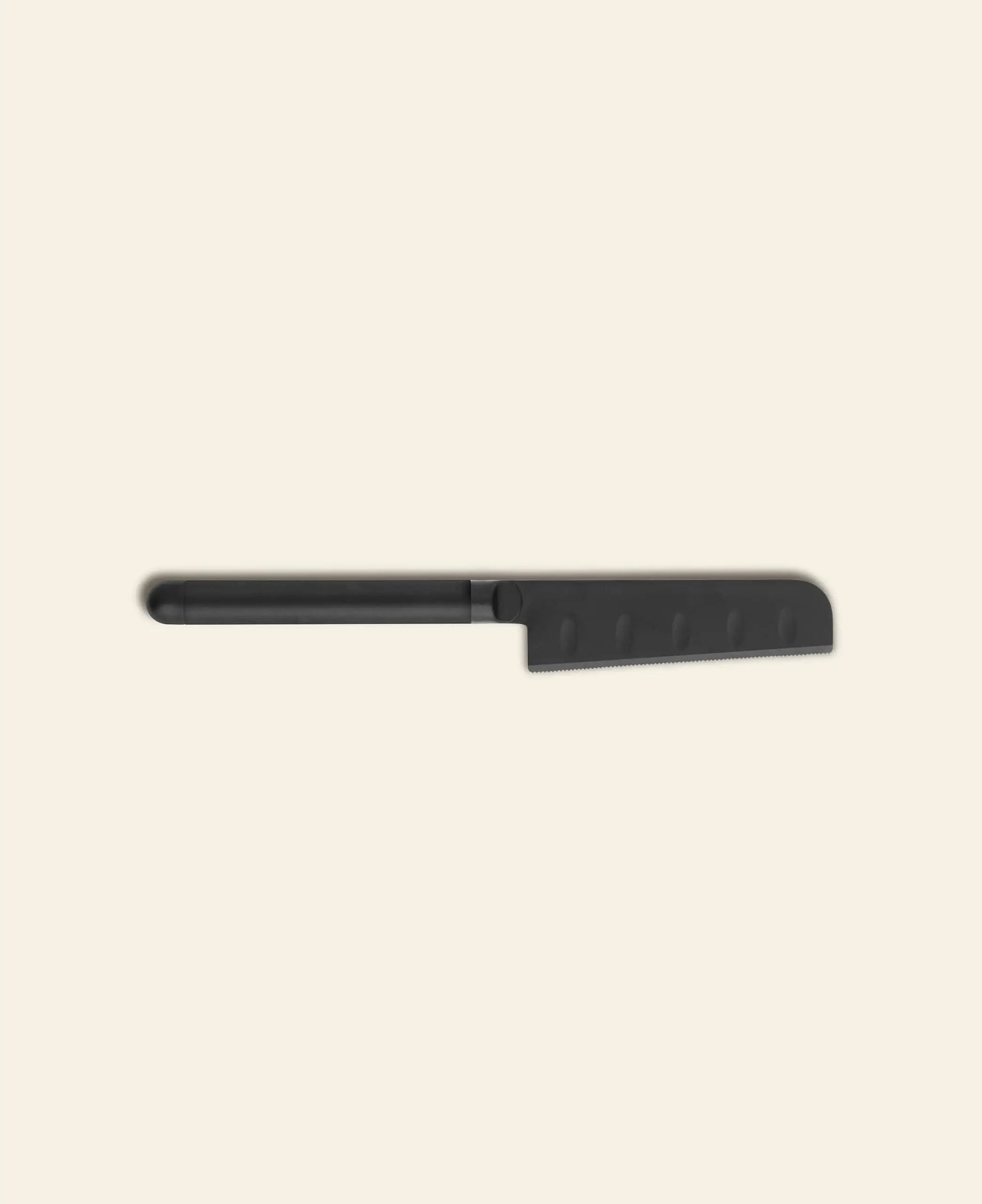 The Normann Copenhagen Pebble Cheese Knife by Normann Copenhagen features a black, serrated blade with a straight handle and rounded tip, inspired by Scandinavian design, shown on a light beige background.