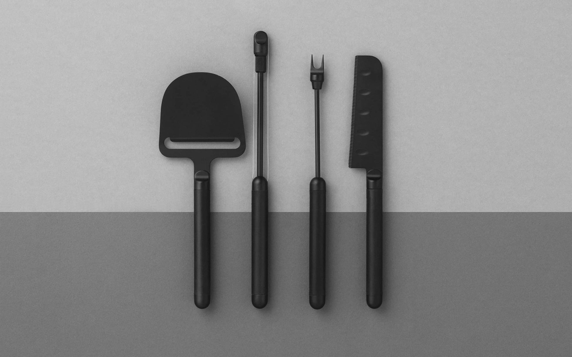 The Normann Copenhagen Pebble Cheese Knife by Normann Copenhagen is displayed on a two-tone gray background, ideal for the modern host who appreciates sleek Scandinavian design.