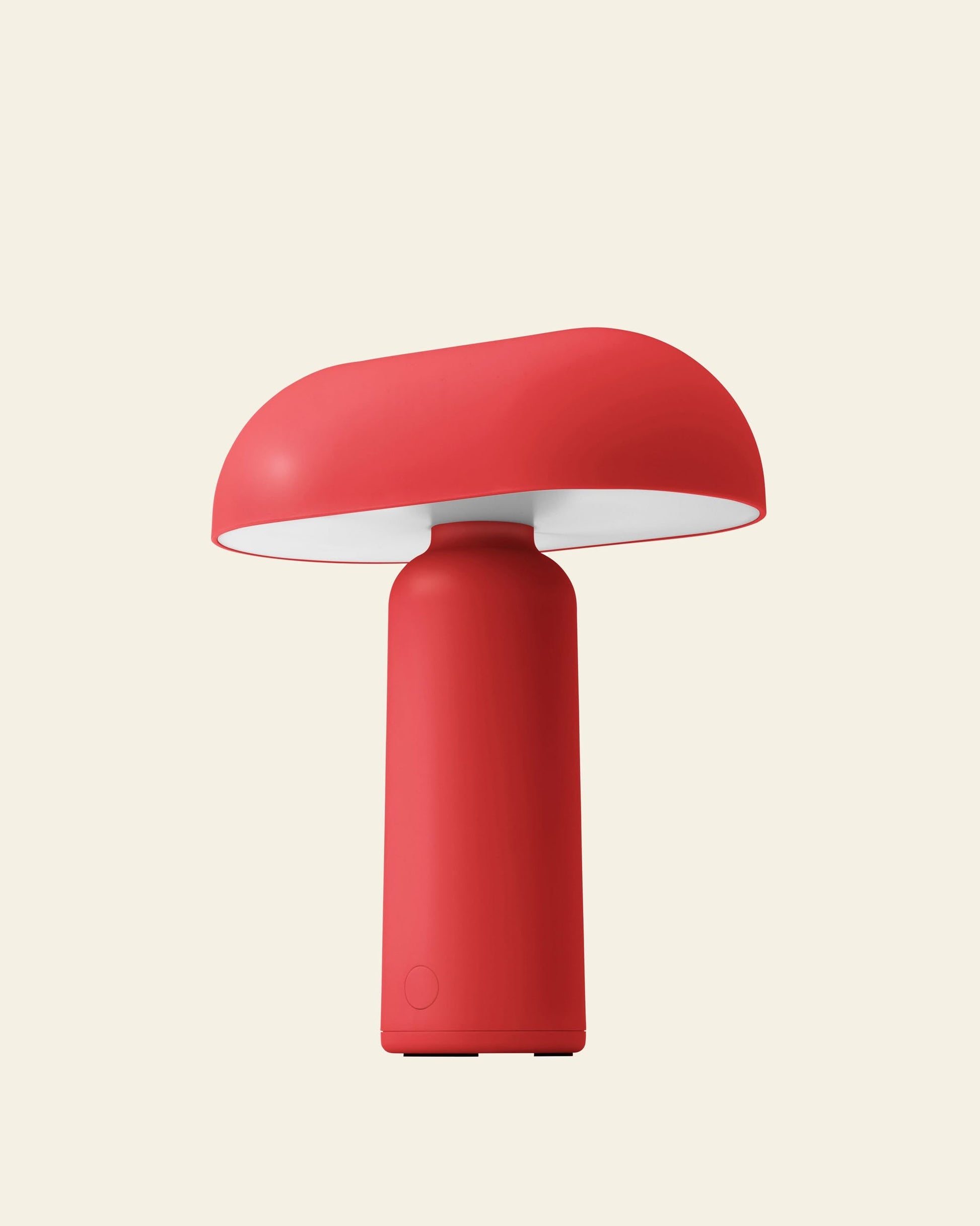 The Normann Copenhagen Porta Table Lamp is a modern, red portable lamp with a cylindrical base and wide, mushroom-like shade—sleekly designed by Normann Copenhagen and set against a light beige background.