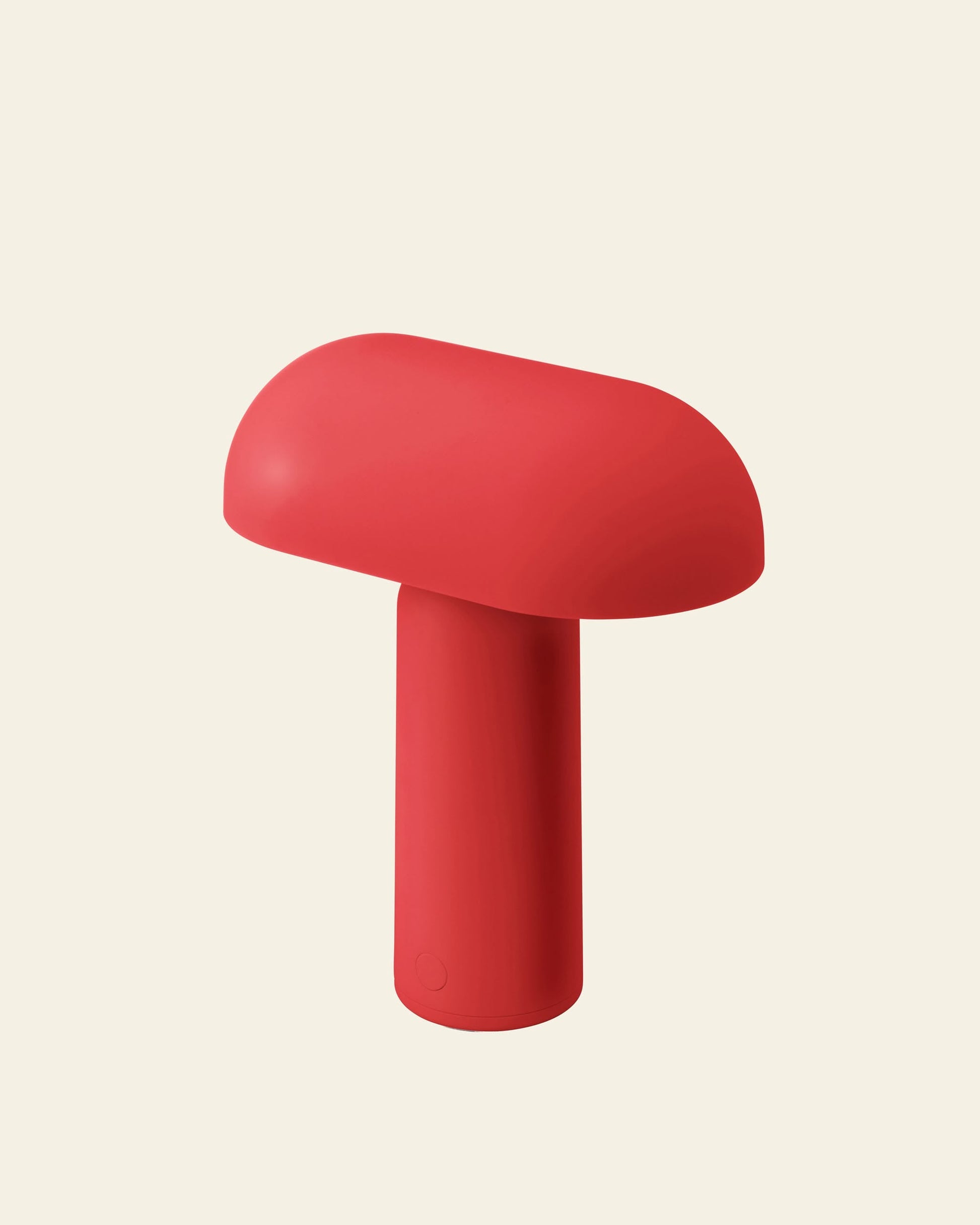The Normann Copenhagen Porta Table Lamp is a red, mushroom-shaped portable lamp with a smooth top and cylindrical stem, showcasing modern design by Normann Copenhagen against a plain light beige background.