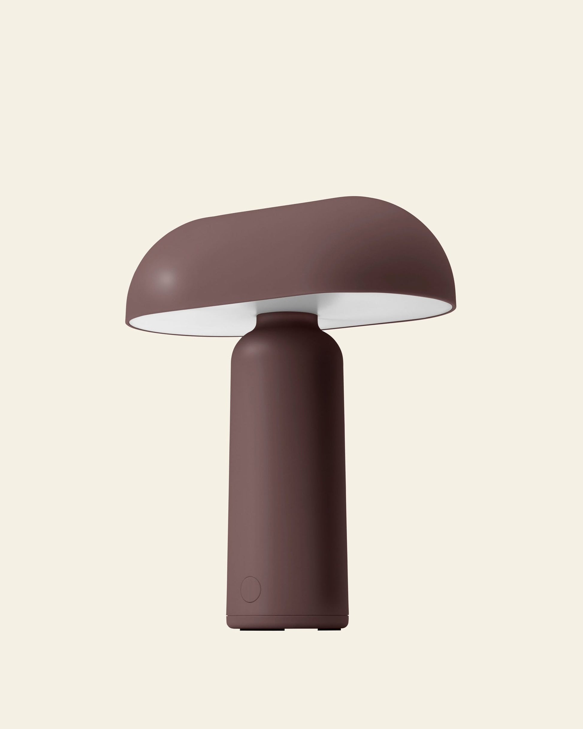 The Normann Copenhagen Porta Table Lamp by Normann Copenhagen features a matte brown finish, modern minimalist design, rounded mushroom shade, and cylindrical base, shown against a plain light beige background.