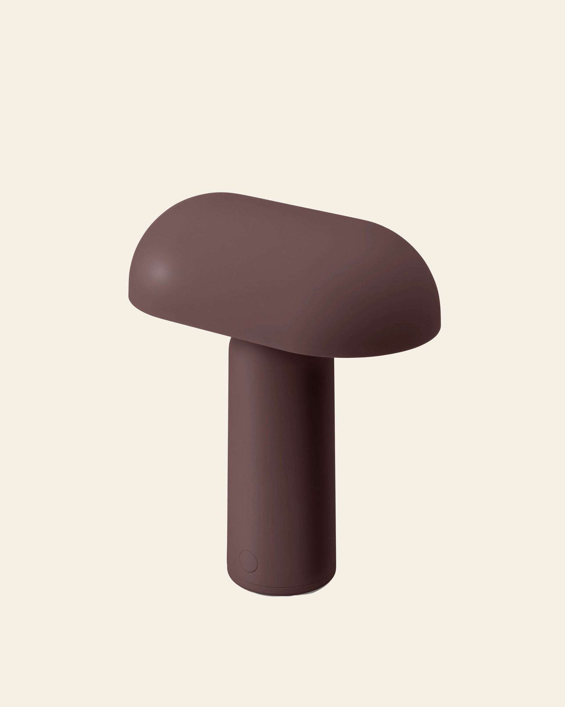 The Normann Copenhagen Porta Table Lamp by Normann Copenhagen is a brown, modern, mushroom-shaped portable lamp with a rounded top and cylindrical base, shown against a plain light beige background.
