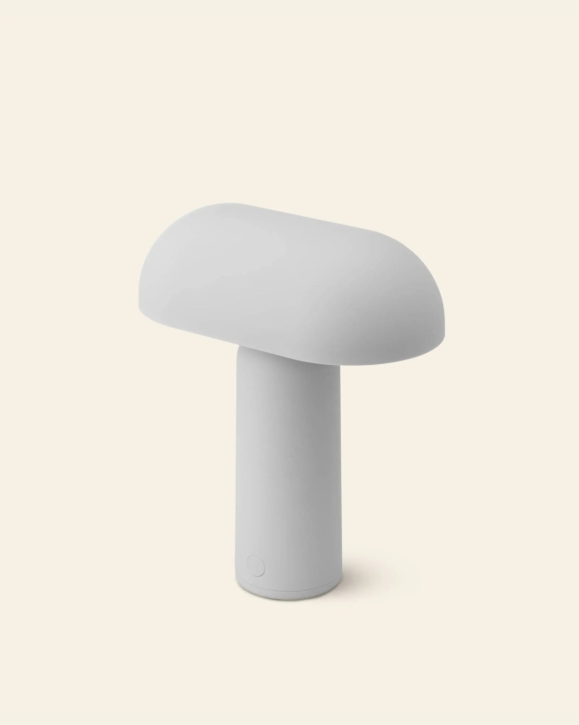 The Normann Copenhagen Porta Table Lamp by Normann Copenhagen features a minimalist, modern mushroom-inspired design with a rounded top and cylindrical base—an ideal portable lamp for contemporary decor lovers.