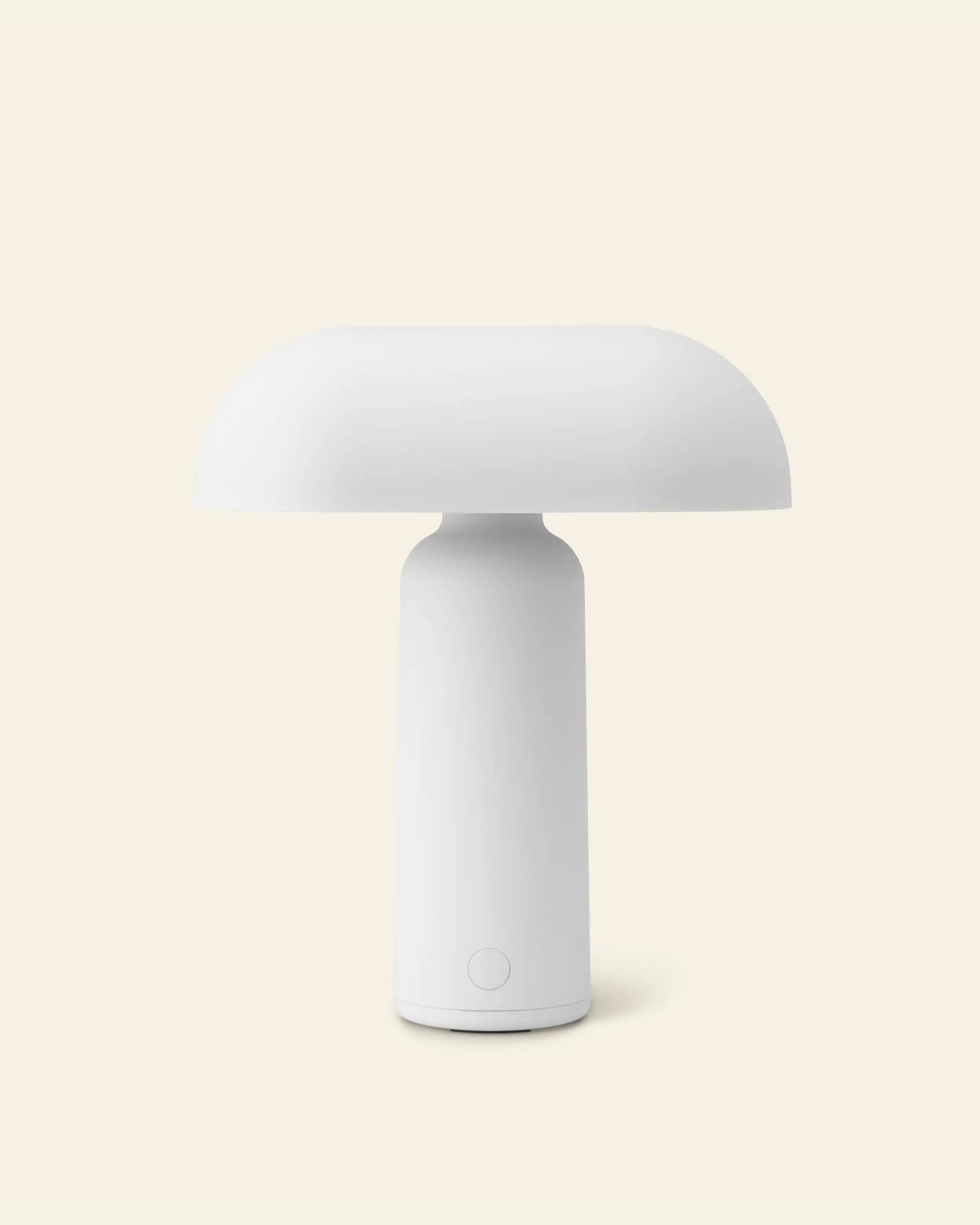 The Normann Copenhagen Porta Table Lamp features a modern minimalist design, with a dome-shaped shade and cylindrical base by Normann Copenhagen, shown against a plain light beige background.