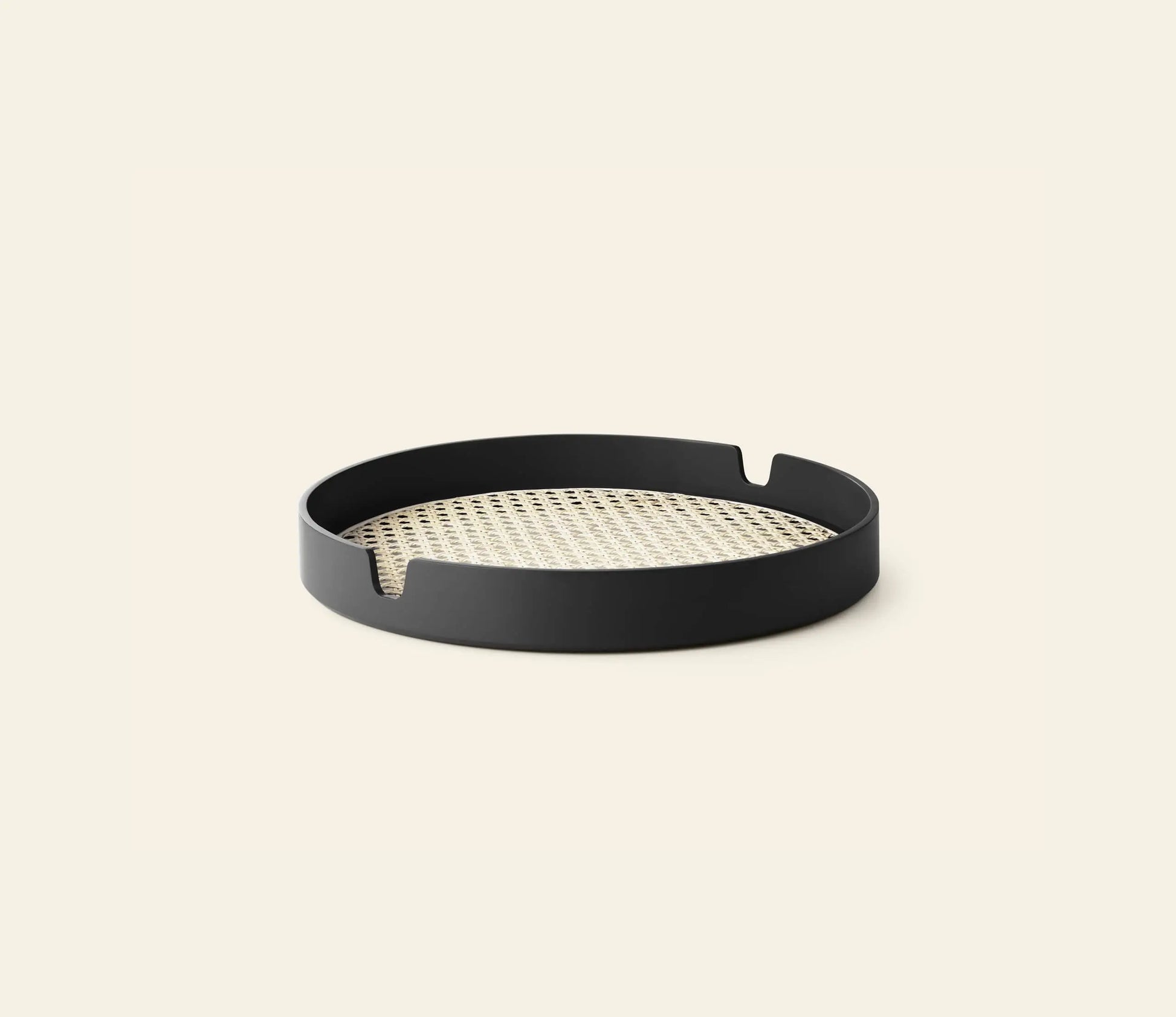 The Normann Copenhagen Salon Tray, 35cm, features a round black frame with a low rim, two small cut-out notches, and a woven bamboo cane base. Brand: Normann Copenhagen. Displayed on a plain light background.