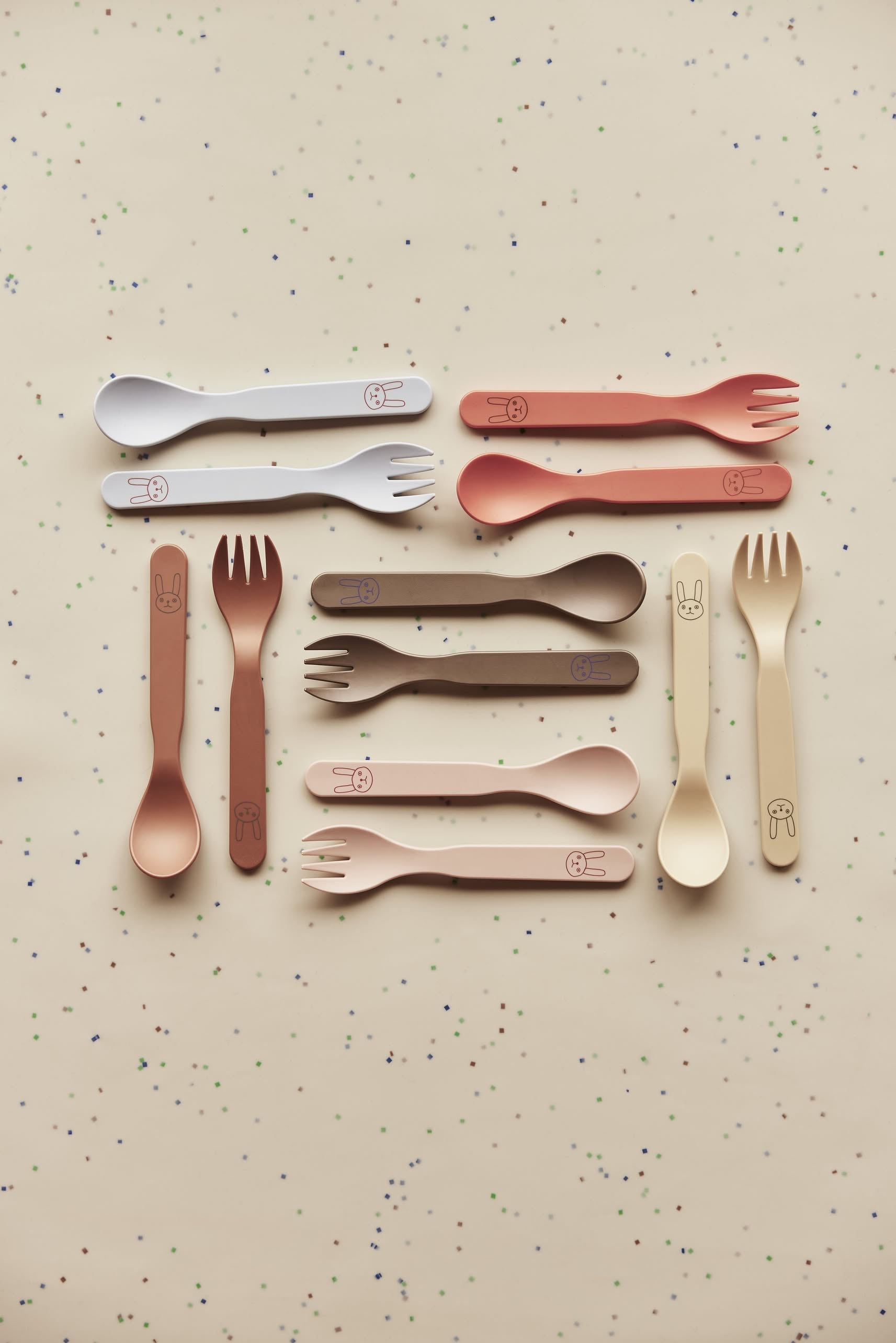The OYOY Living Design Pullo Cutlery Set features pastel PLA sporks and spoons with cute bunny faces, neatly arranged on a light background—perfect eco-friendly toddler cutlery from OYOY Living Design.
