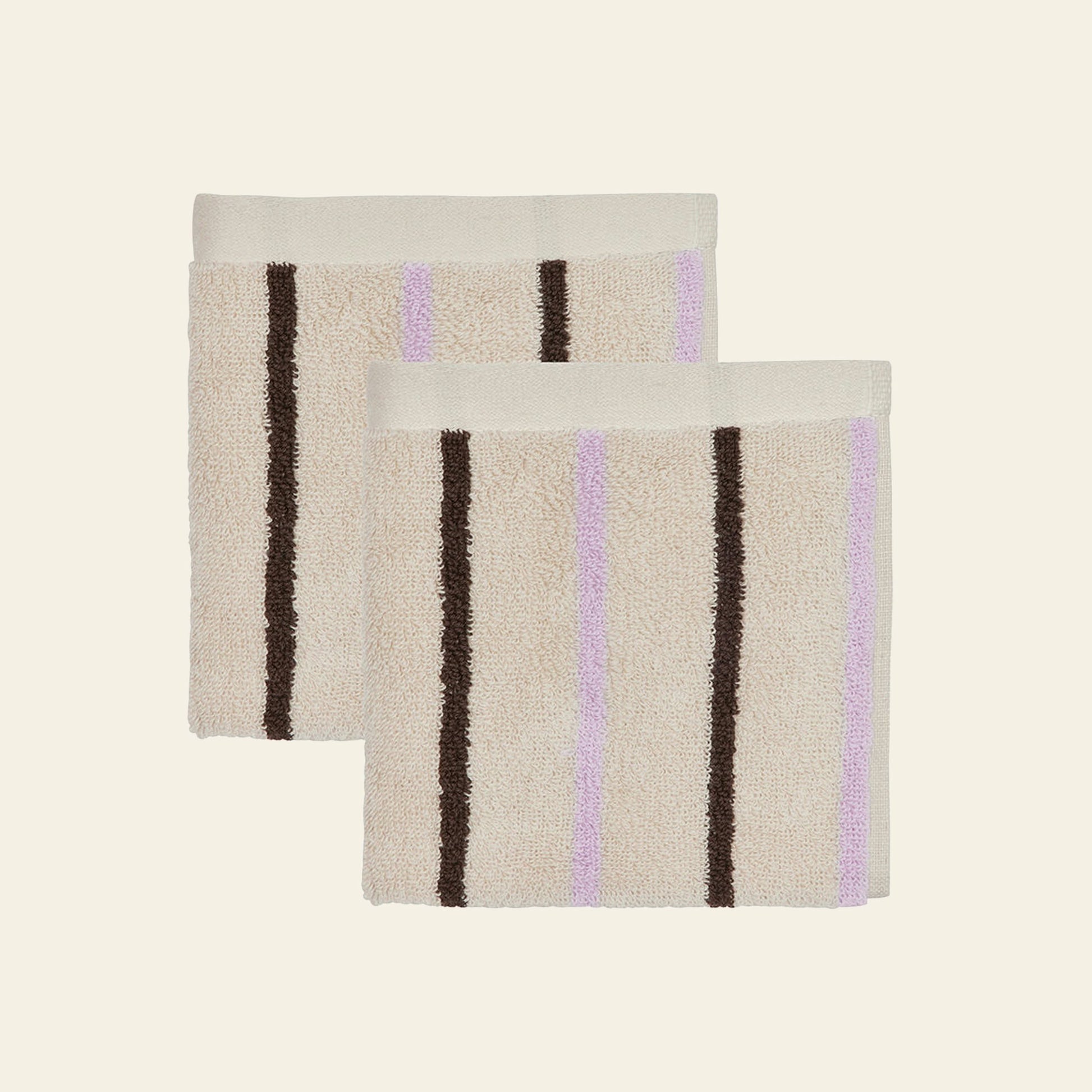 Two beige OYOY Living Design Raita Wash Cloths, made from organic cotton terry with vertical brown and light purple stripes, are shown side by side on a plain light background. Sold as a pack of 2.