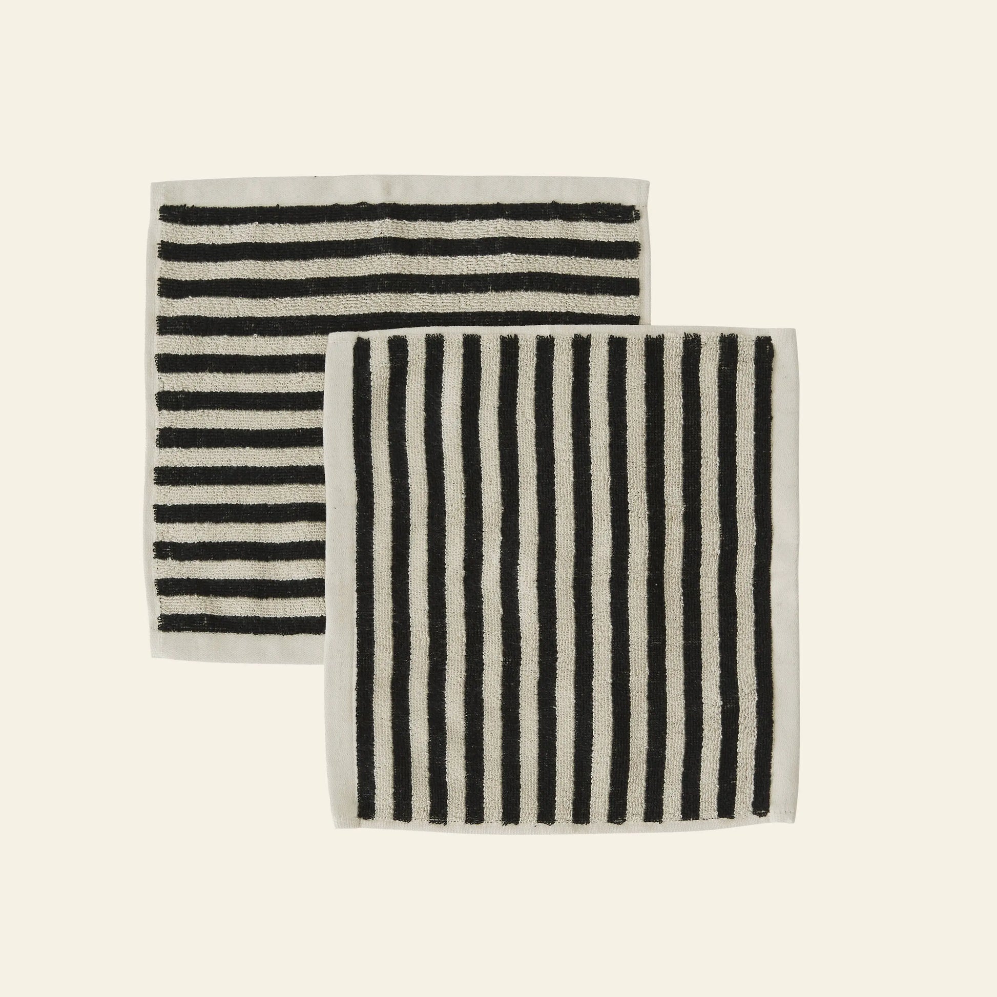 The OYOY Living Design Raita Wash Cloth, Pack of 2, features organic cotton terry cloths with black and white stripes—one horizontal, one vertical—each bordered in white and displayed side by side on a plain background.