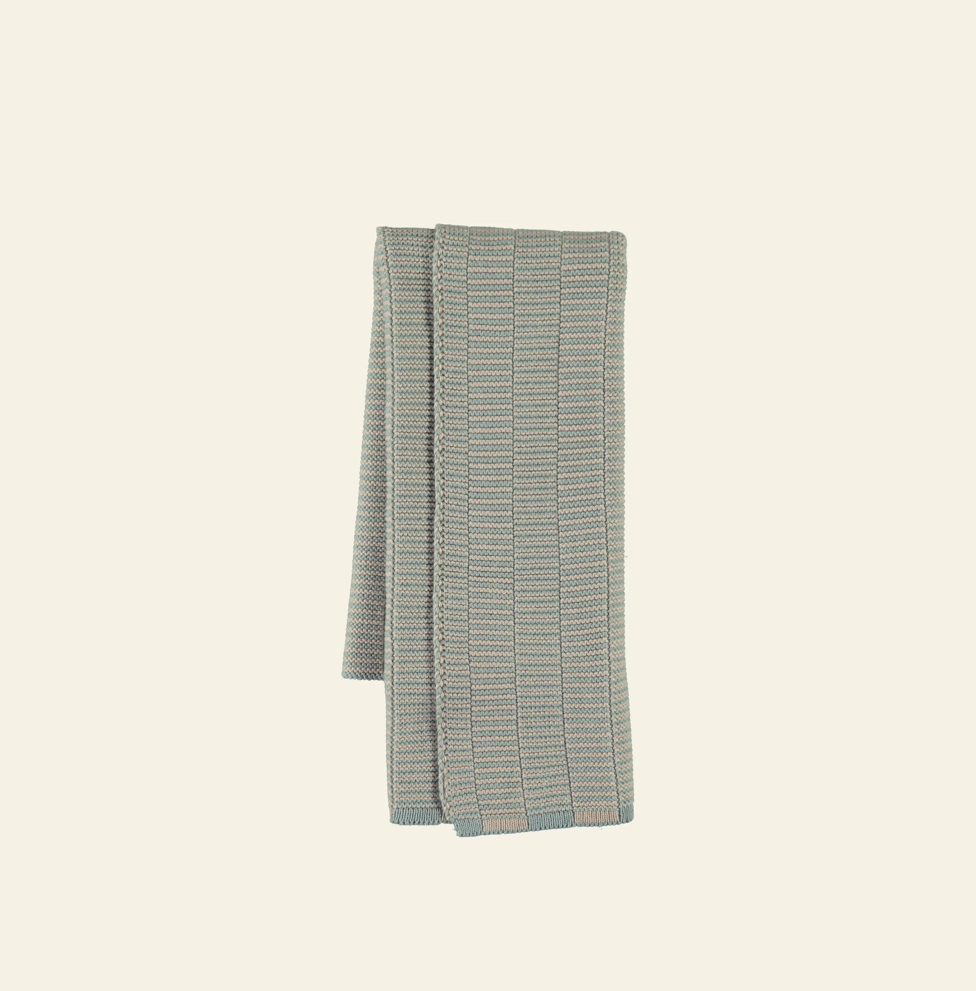 The OYOY Living Design Stringa Mini Towel, a light blue and beige checkered hand towel crafted from knitted organic cotton, is shown neatly folded against a plain off-white background.