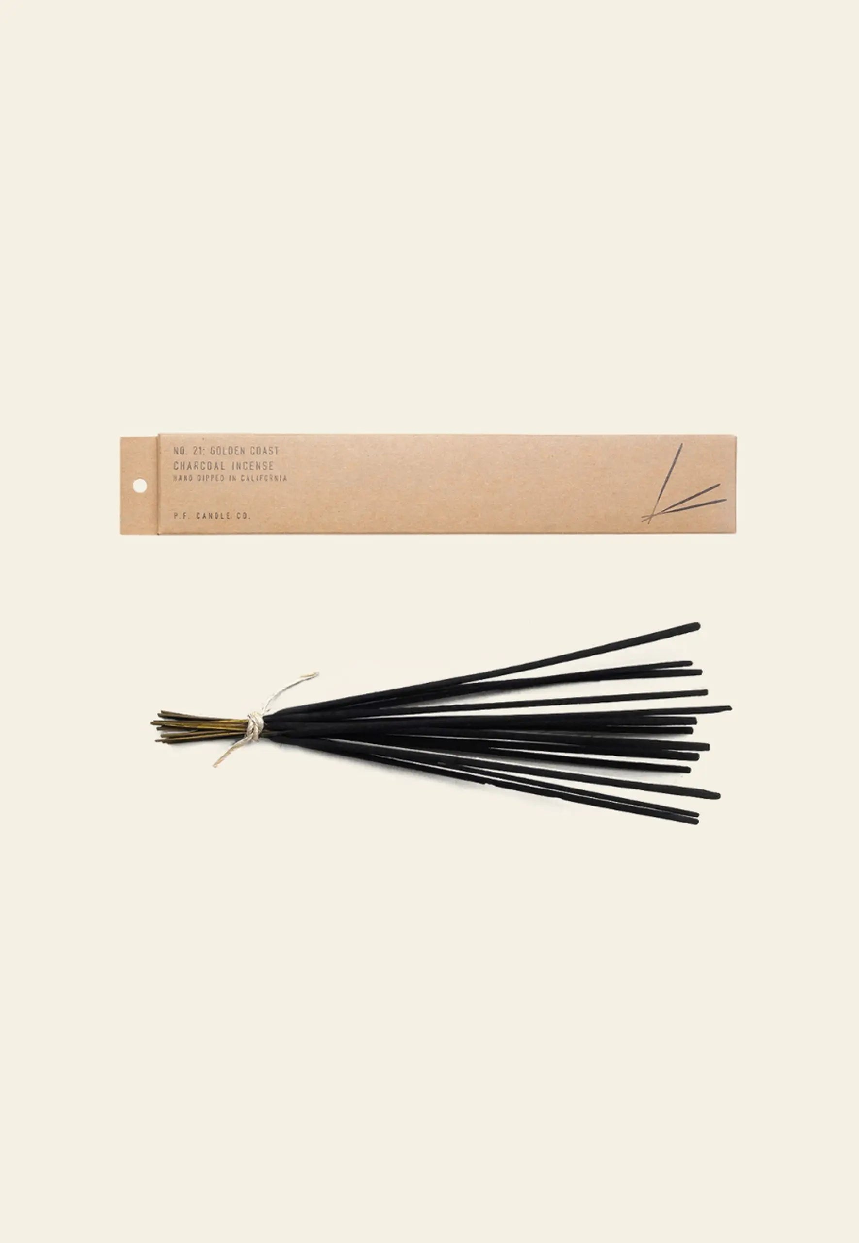 A bundle of black incense sticks tied with string rests beneath a brown rectangular P.F. Candle Co. Classic Incense box, all against a plain off-white background.