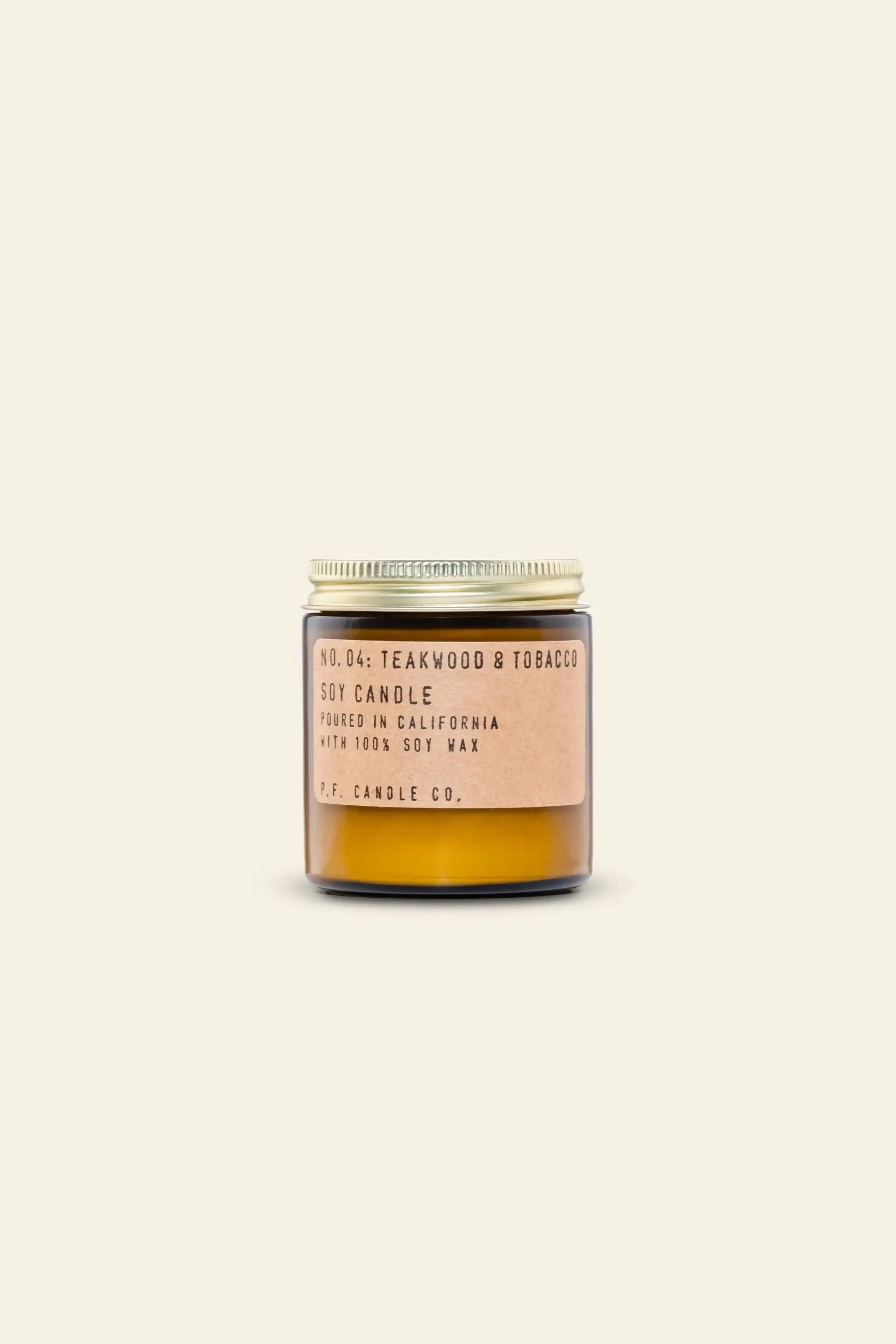 The P.F. Candle Co. No. 4 Teakwood & Tobacco 3.5 oz Mini Candle features a small amber glass jar with a beige label, set against a simple light background, and is made by P.F. Candle Co. in California.