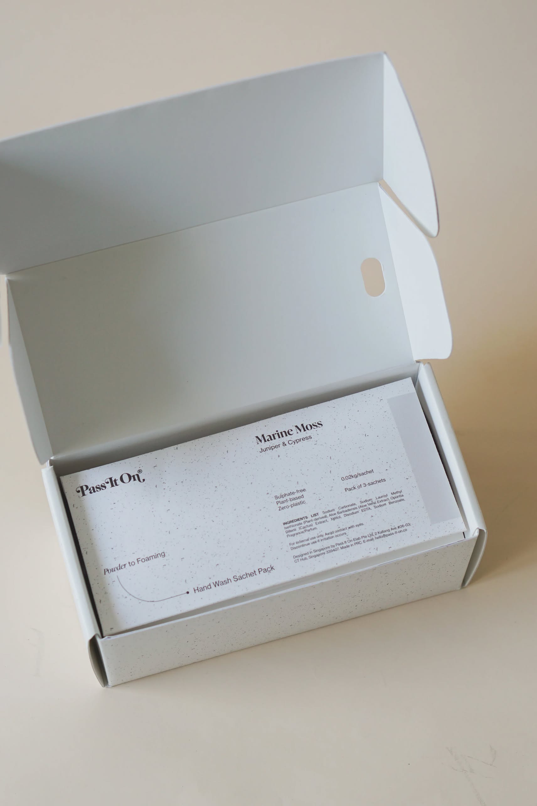 An open white box contains a Pass It On 0.02 Refillable Hand Wash Set, Pack of 3-Marine Moss, with instructions printed on each sachets front.