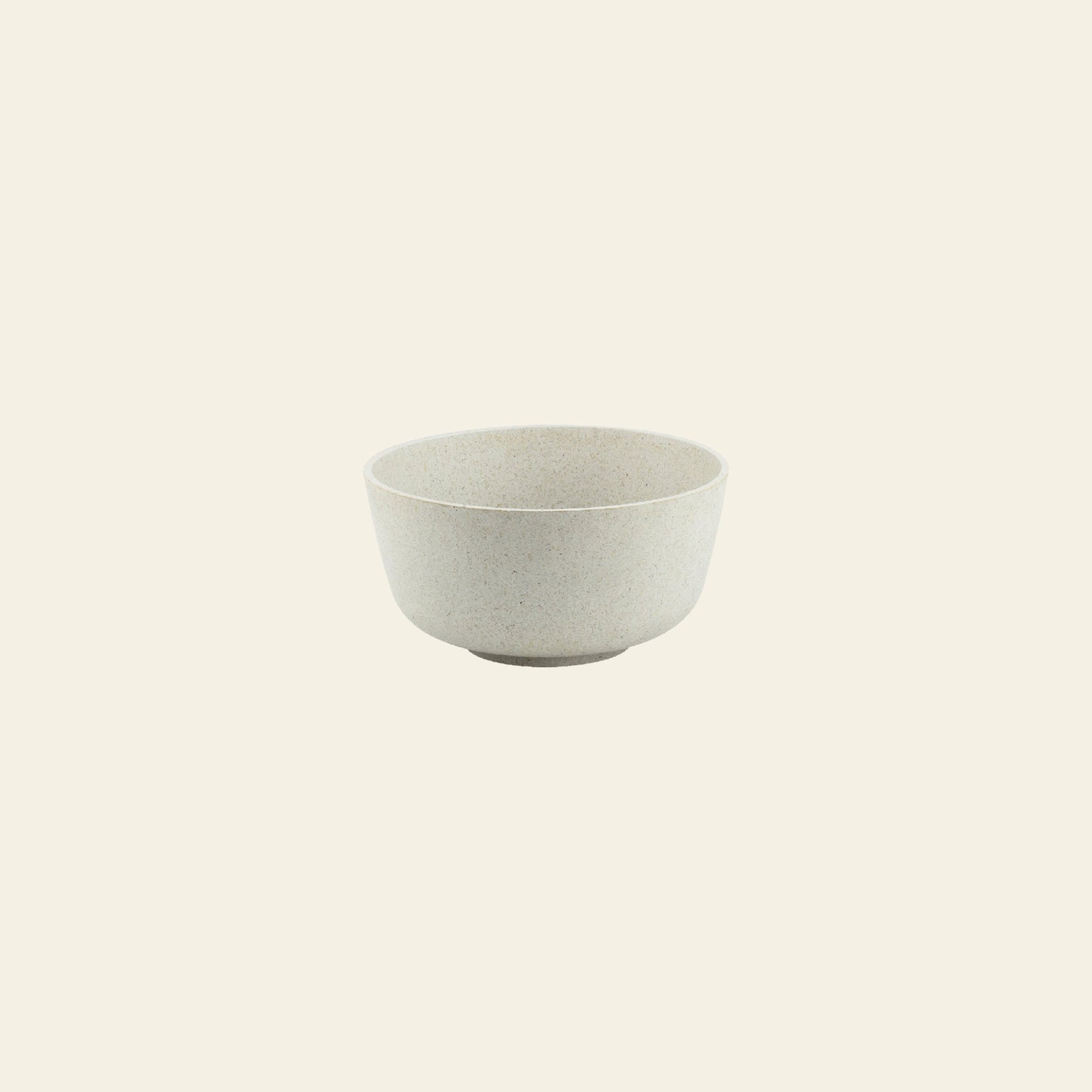 The Pass It On Capsule Bowl, Rice Husk by Pass It On—a plain, light gray bowl made from upcycled rice husks—sits empty on a pale beige background, showcasing its minimalist and sustainable design.