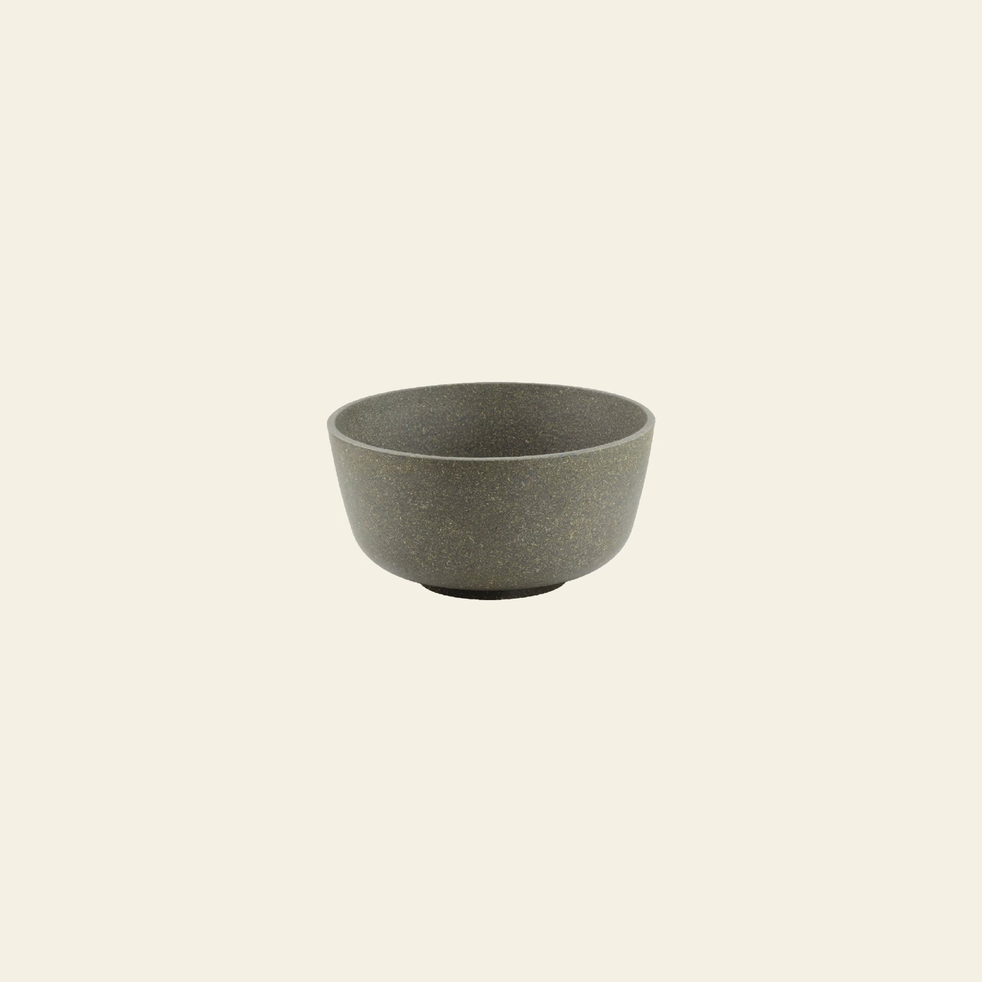 The Pass It On Capsule Bowl, Rice Husk—a small, round gray bowl with a matte finish made from upcycled rice husks by Pass It On—is centered on a plain light beige background, highlighting sustainable design.