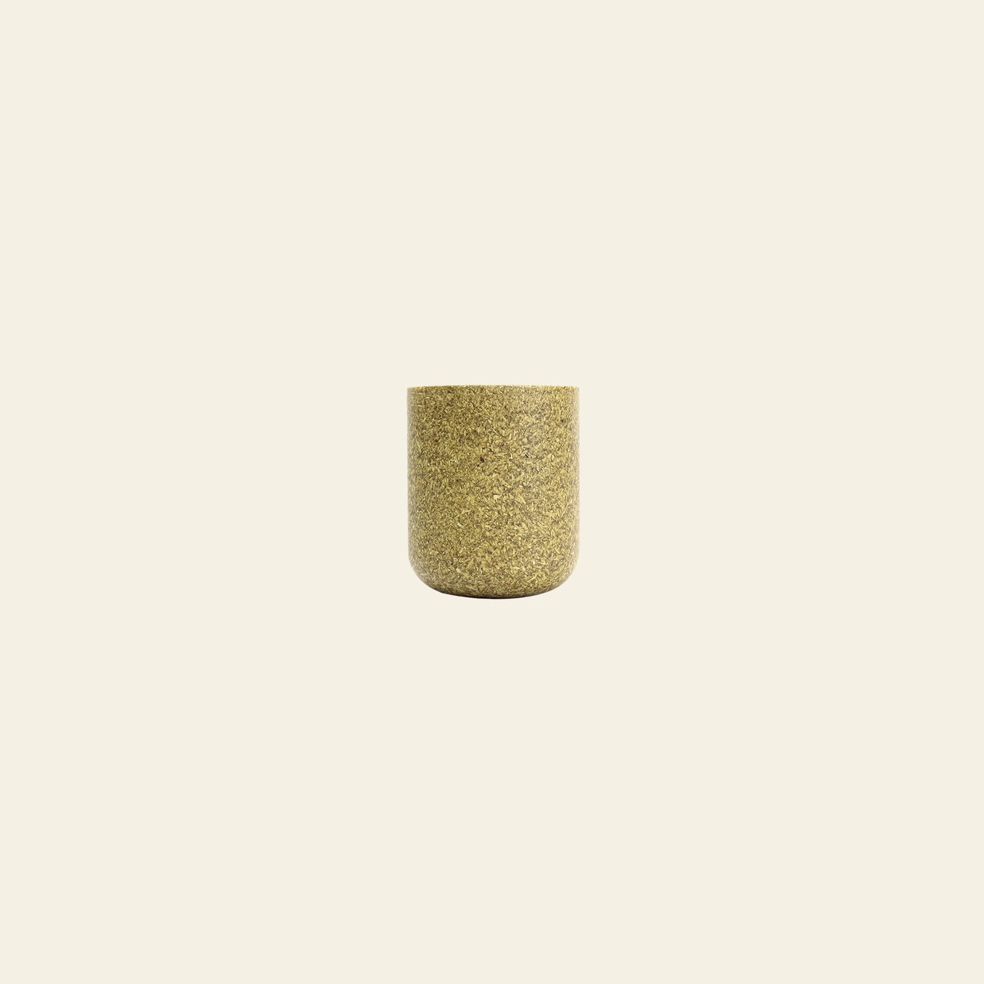 The Pass It On Capsule Cup, Rice Husk by Pass It Onâa small cylindrical cup made from upcycled rice husks in mottled goldâsits centered on a plain beige background, offering an eco-conscious choice for your daily routine.