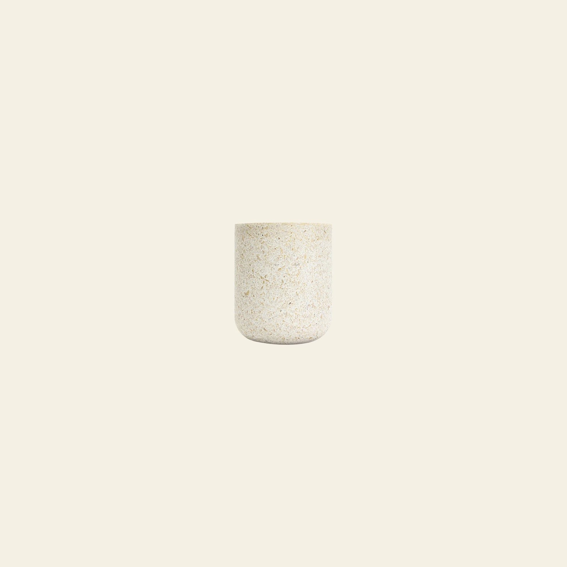 A small, round Pass It On Capsule Cup, Rice Husk by Pass It On, made from upcycled rice husks with a smooth, speckled light beige finish, is centered on a plain off-white background.