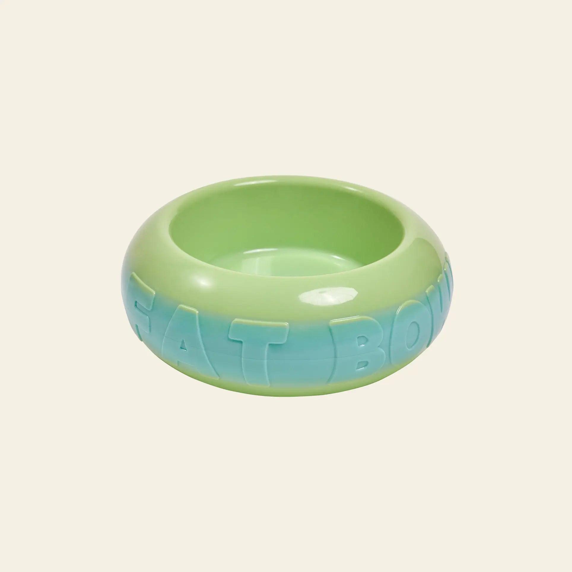 The Plastic Ark Fat Bowl by Plastic Ark is a round, green pet bowl made from recycled plastic, with a modular design and blue gradient EAT BOWL lettering on the side, shown on a light beige background.