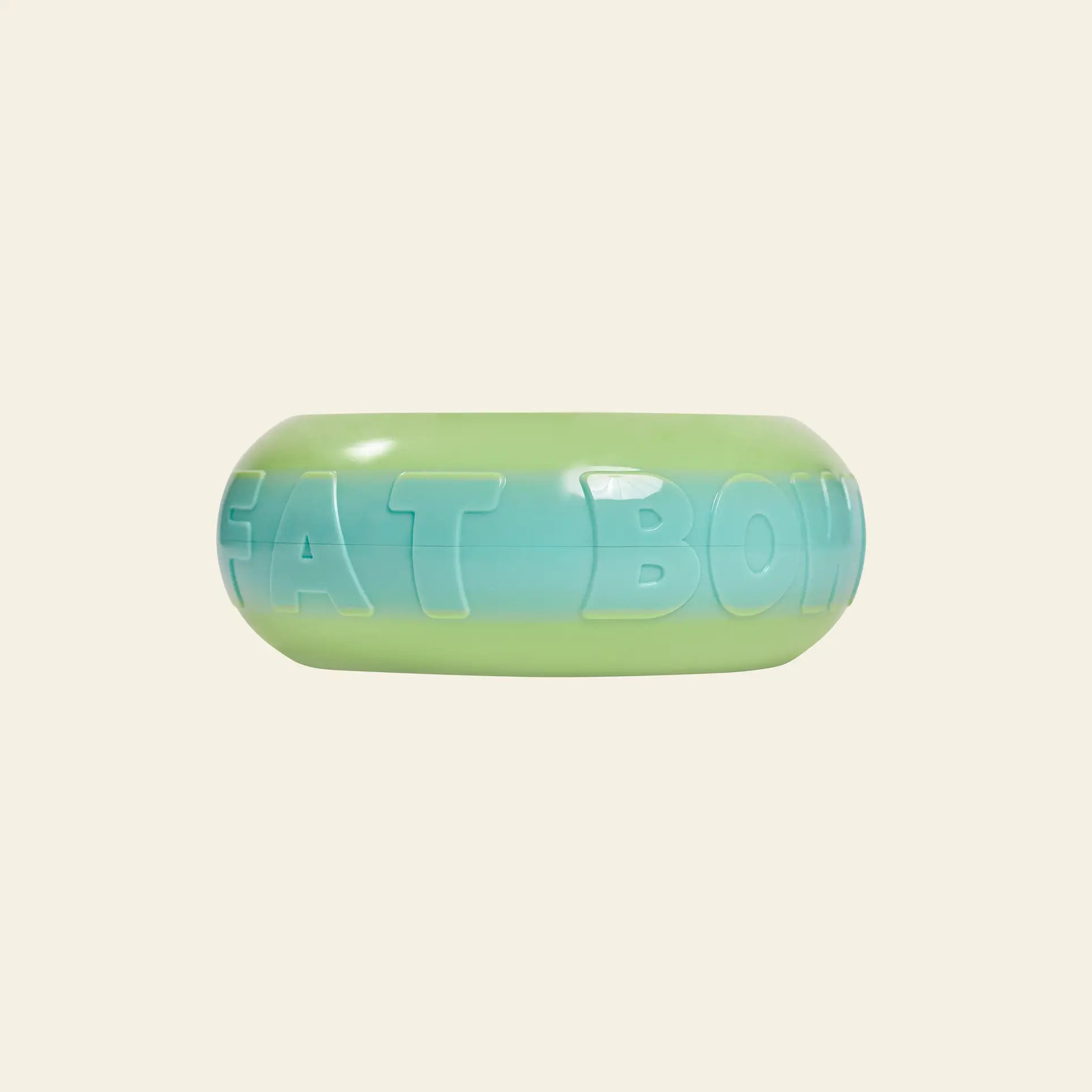 The Plastic Ark Fat Bowl by Plastic Ark is a round, gradient pet bowl in green-to-blue plastic with embossed FAT BOWL lettering, inspired by modular design and photographed against a plain beige background.
