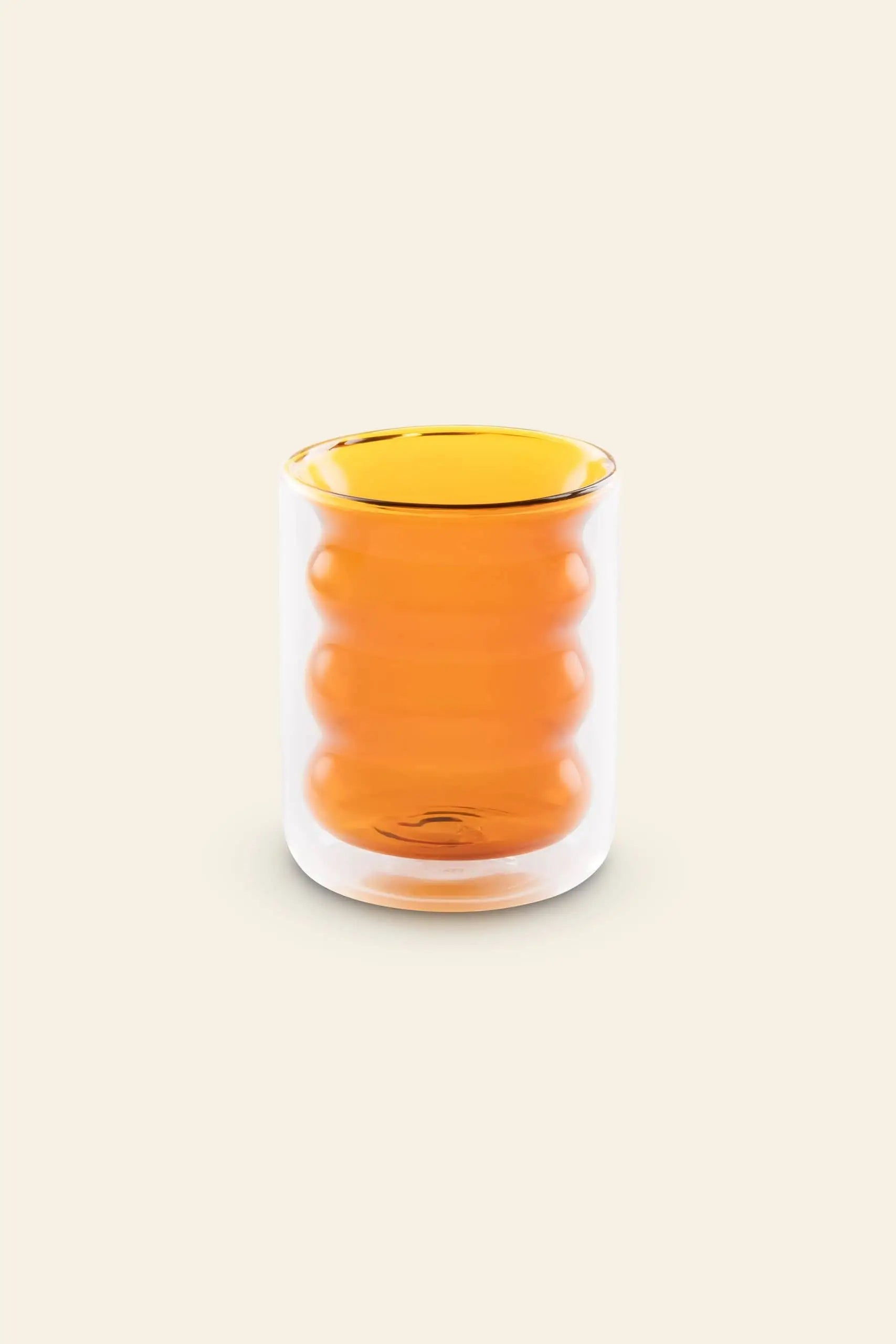 The Poketo Double Wall Groovy Cup by Poketo is a hand-blown borosilicate glass with a curved, ribbed orange inner layer, shown on a plain beige background.
