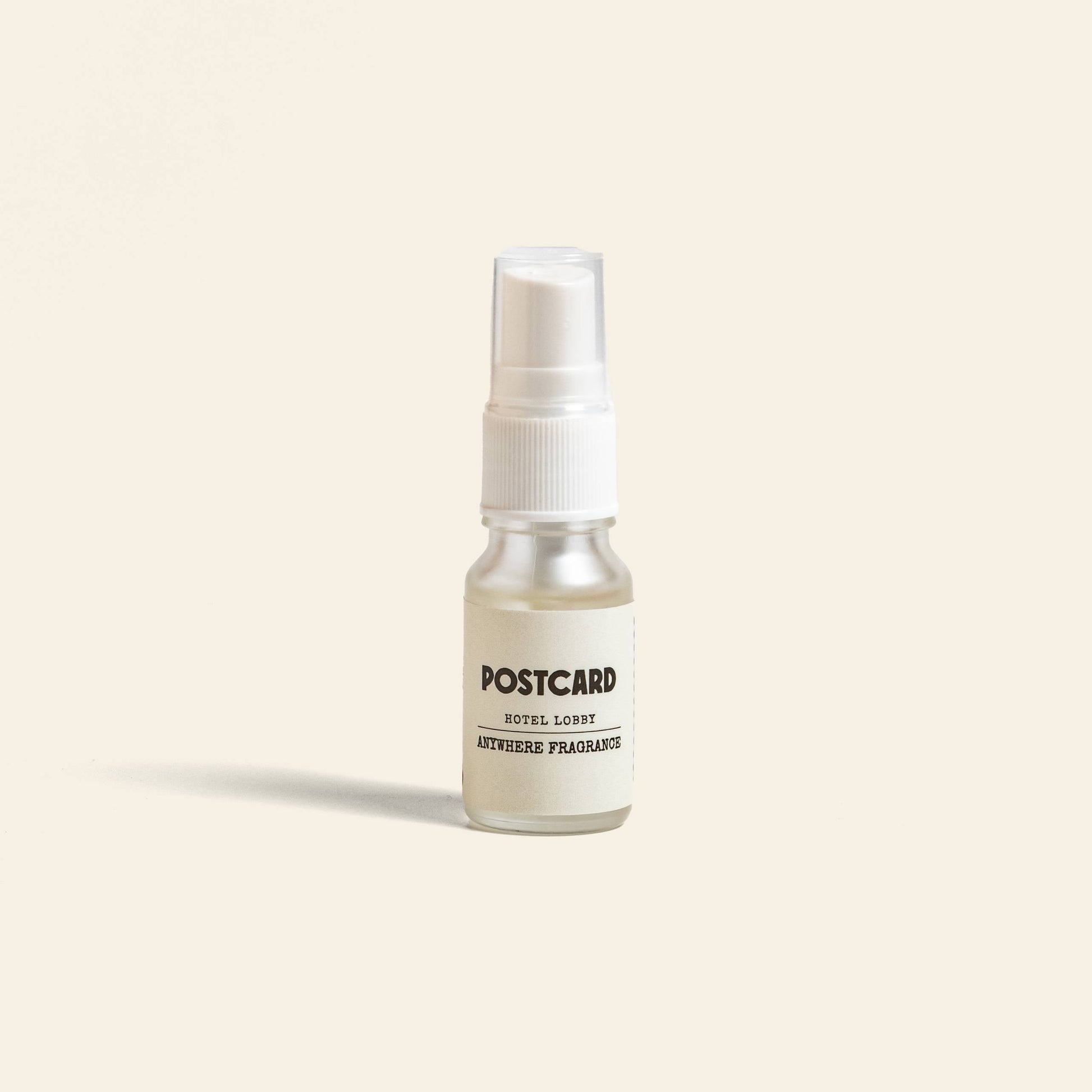 A 10ml Postcard Anywhere Fragrance in Hotel Lobby scent stands upright on a light beige background, capturing the luxury of hotel ambiance with this bestselling fragrance by Postcard.