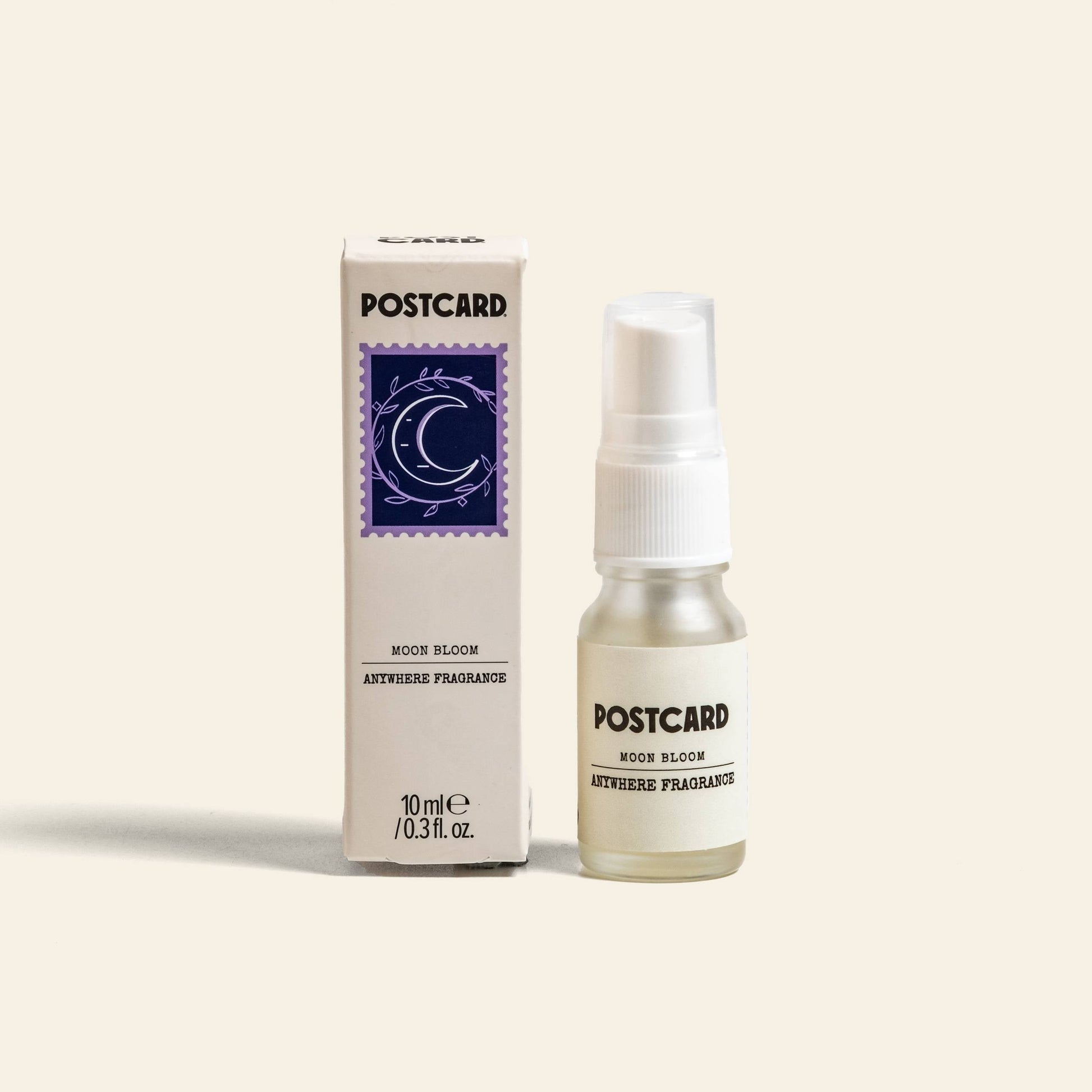 A 10ml Postcard Anywhere Fragrance in Moon Bloom sits next to its matching box with a crescent moon and star design, offering an enchanting, delicately scented aroma by Postcard.