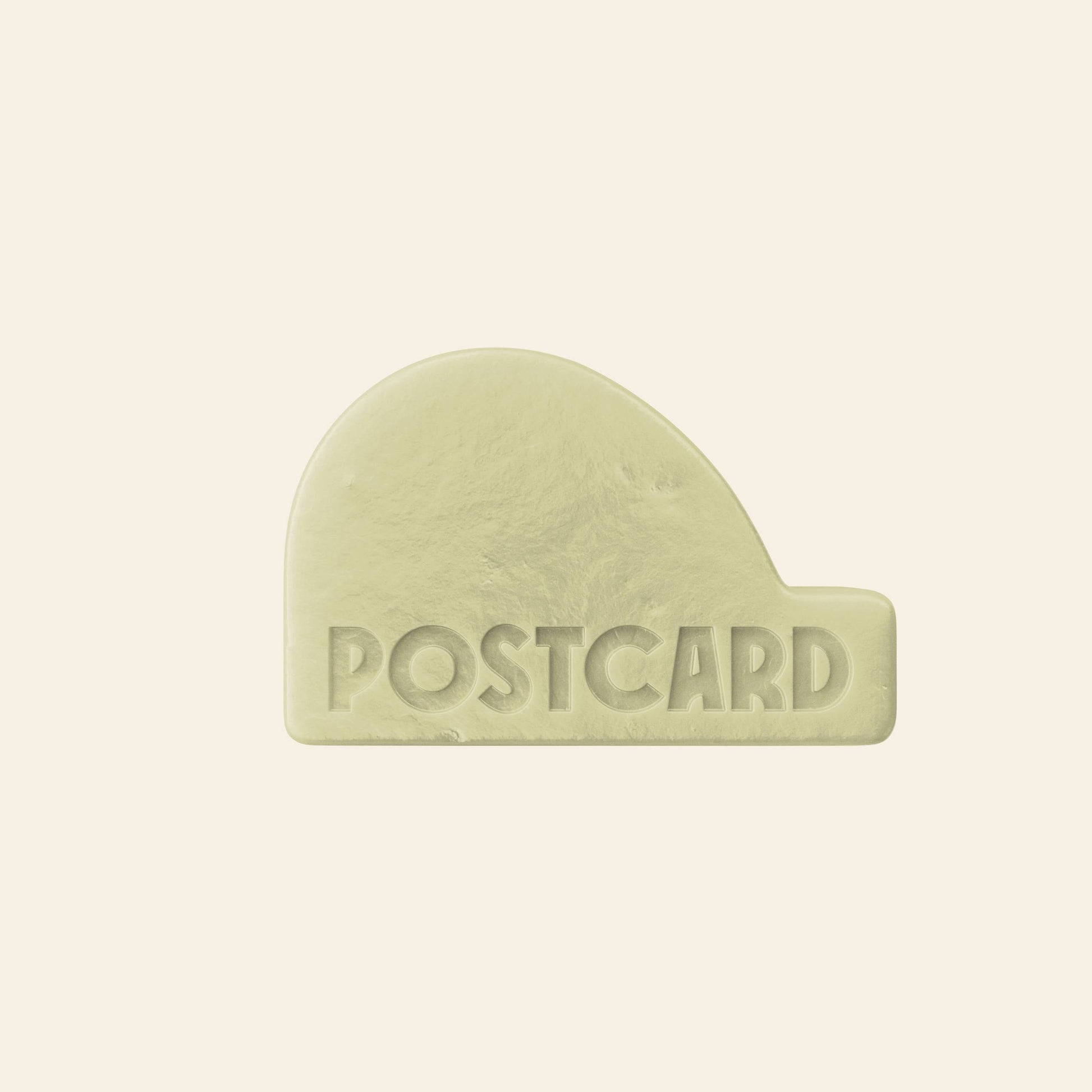 A pale yellow, rounded rectangular Postcard Head-To-Toe Bar (100g, Java Jungle) with POSTCARD embossed in uppercase on a beige background—an all-in-one, sulfate-free bar designed to combat hair loss.