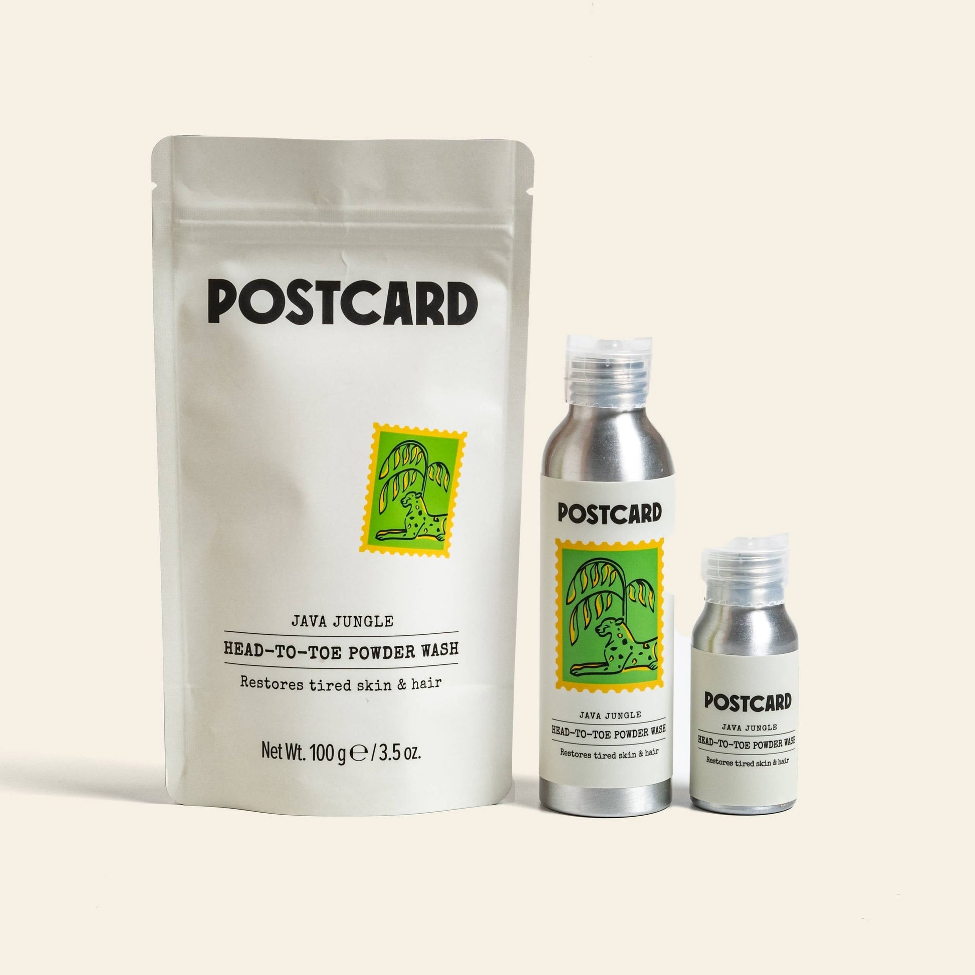 Three POSTCARD Head-To-Toe Powder Wash products (25g, Java Jungle) with a green stamp design: a white resealable pouch and two silver bottles. This sulfate-free powder wash uses Stinging Nettle to revive tired skin and hair.