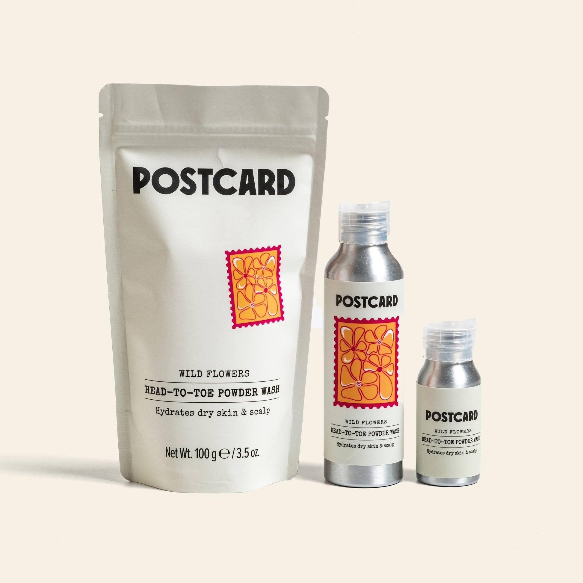 Three Postcard products: a white pouch labeled Postcard Head-To-Toe Powder Wash, 25g - Wild Flowers, plus two silver sulfate-free bottles with matching Postcard and floral designs—one is the Wild Flowers cleanser.