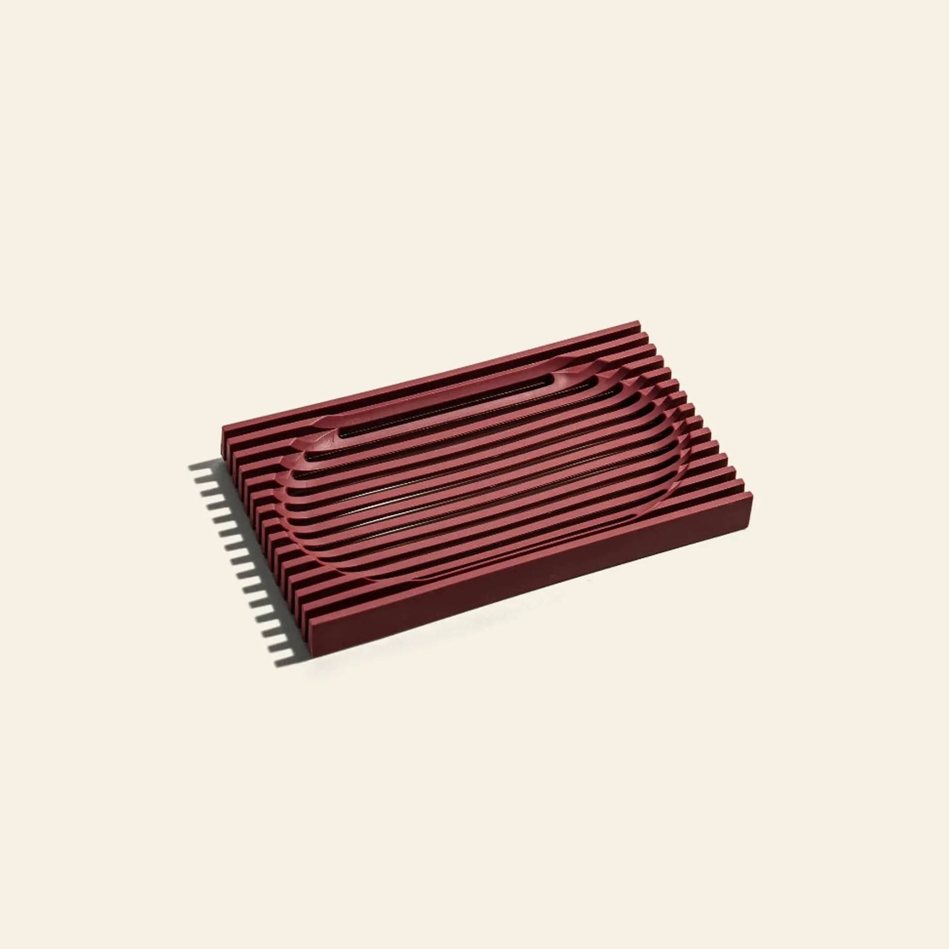 The Postcard Lattice Soap Dish by Postcard features a rectangular, dark red design with raised horizontal ridges on beige resin, making it recyclable and ideal for minimalist or zero-waste lifestyles.