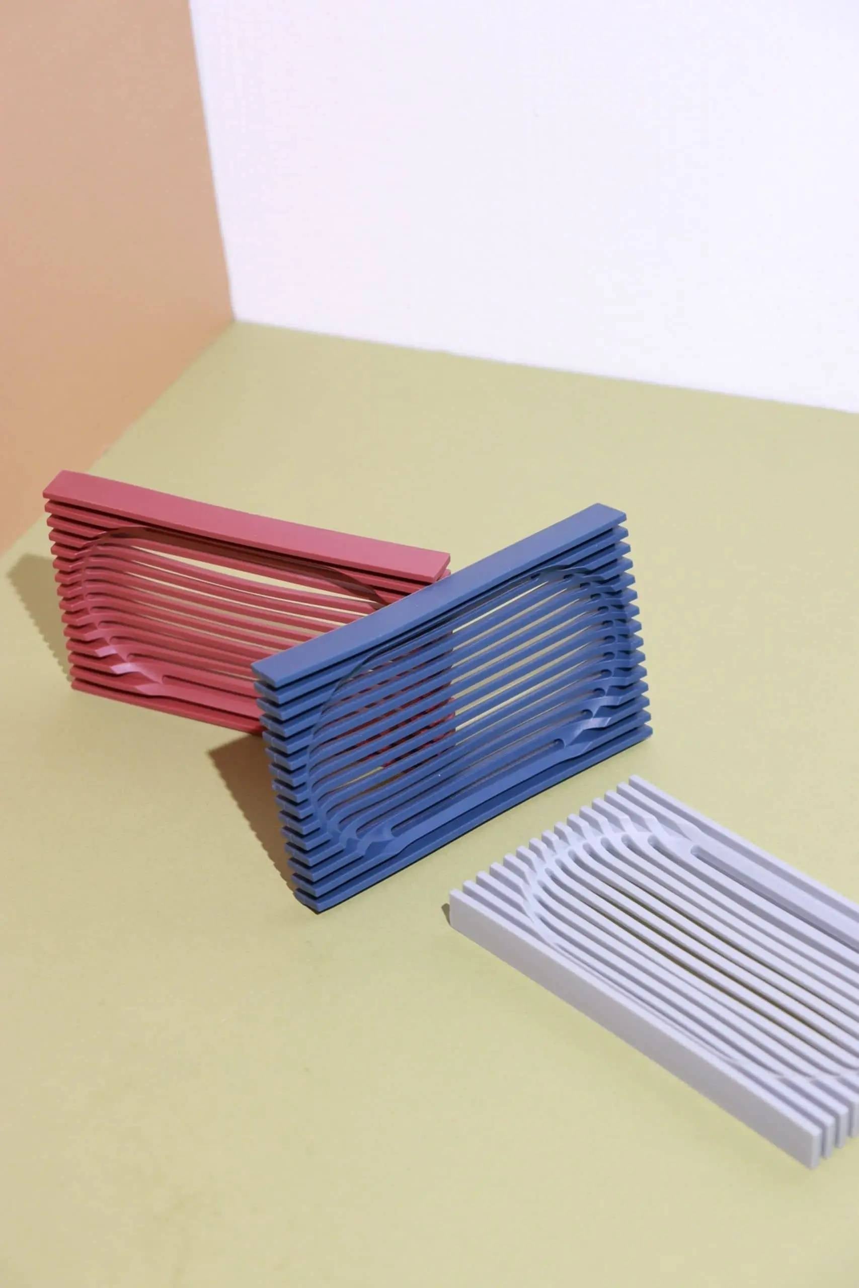Three Postcard Lattice Soap Dishes by Postcard, in pink, blue, and light gray, feature horizontal ridges and a modern look. Made from recyclable resin, they suit a zero-waste lifestyle and are shown arranged on a pastel surface against a two-toned background.