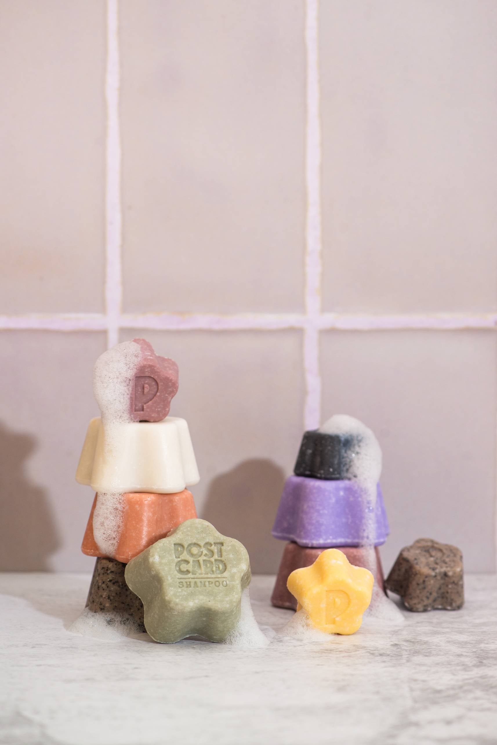 Postcard Shampoo Bar, 60g - Java Jungle by Postcard is arranged on a white surface with bubbles, showcasing its star shape—a gentle, sulfate-free hair care option perfect for vibrant hair.