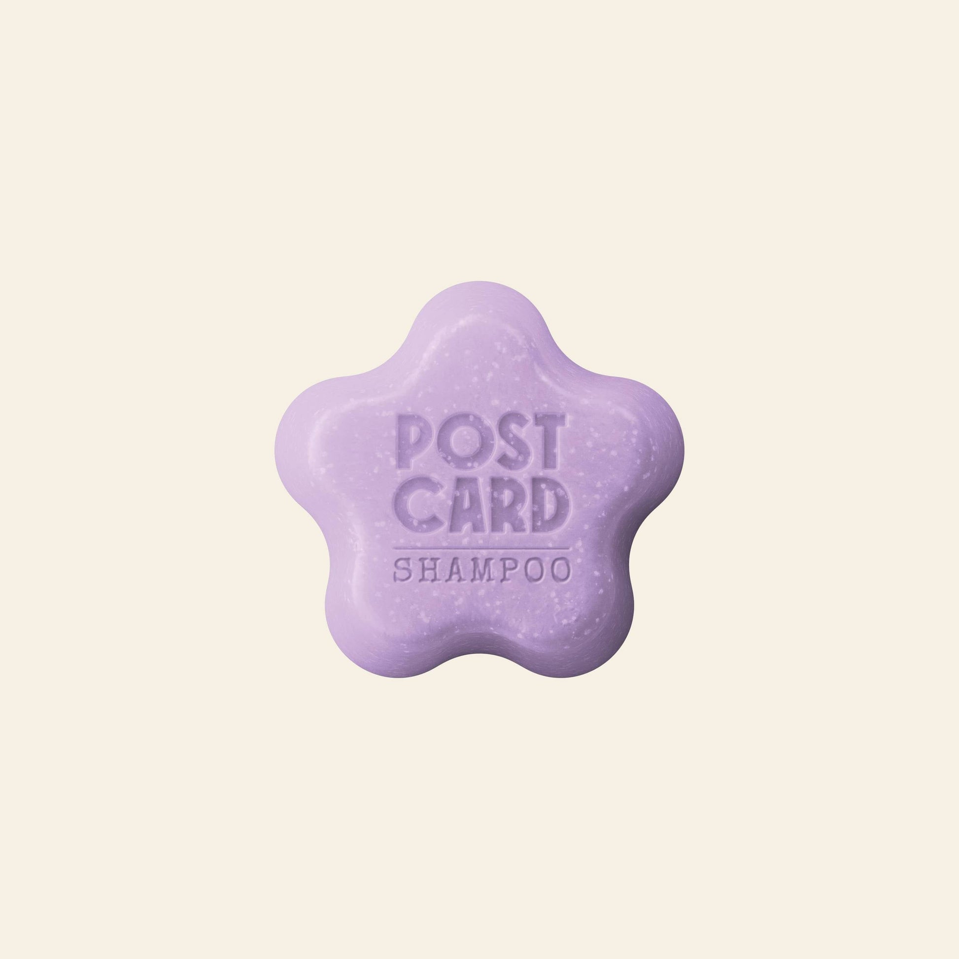 A light purple, star-shaped Postcard Shampoo Bar (60g) in Woodland Retreat scent, embossed with “POST CARD SHAMPOO” and infused with a rejuvenating herbal blend, shown on a plain cream background.