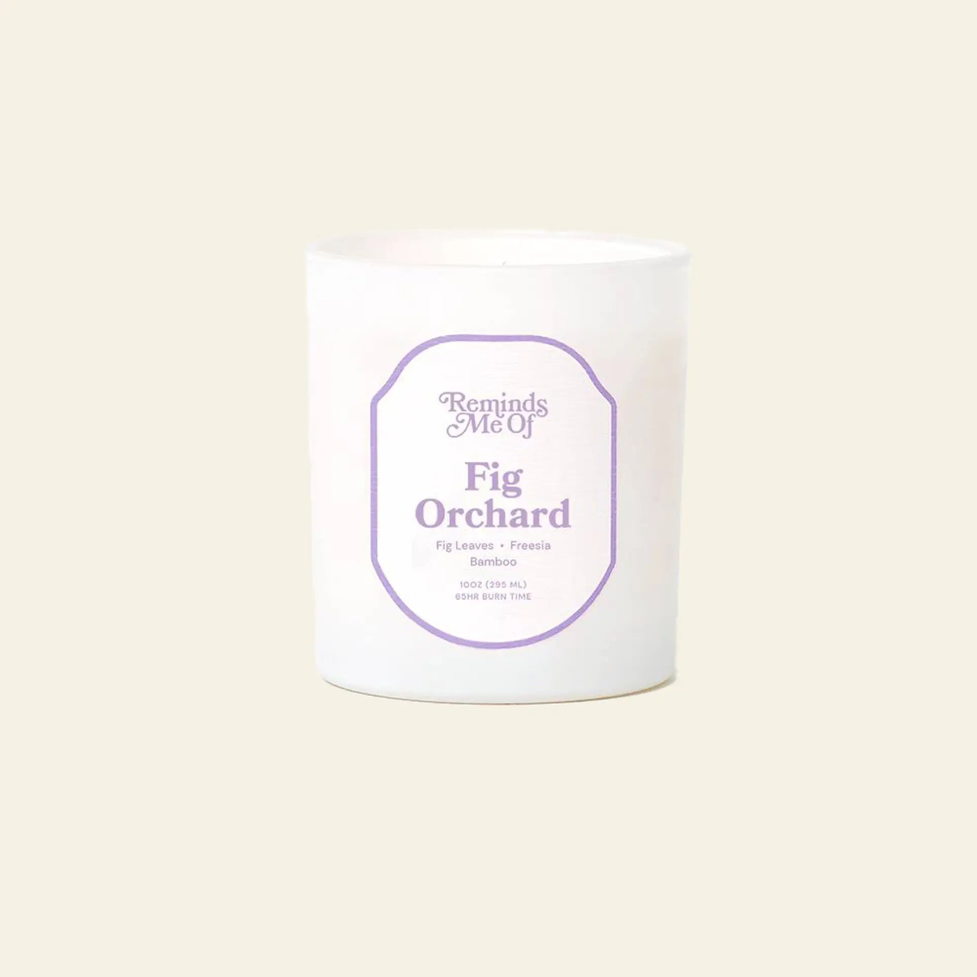 The Reminds Me Of Fig Orchard Candle, 10oz by Reminds Me Of features fig leaves, freesia, and bamboo notes in a frosted glass jar with a white candle, shown against a plain beige background.