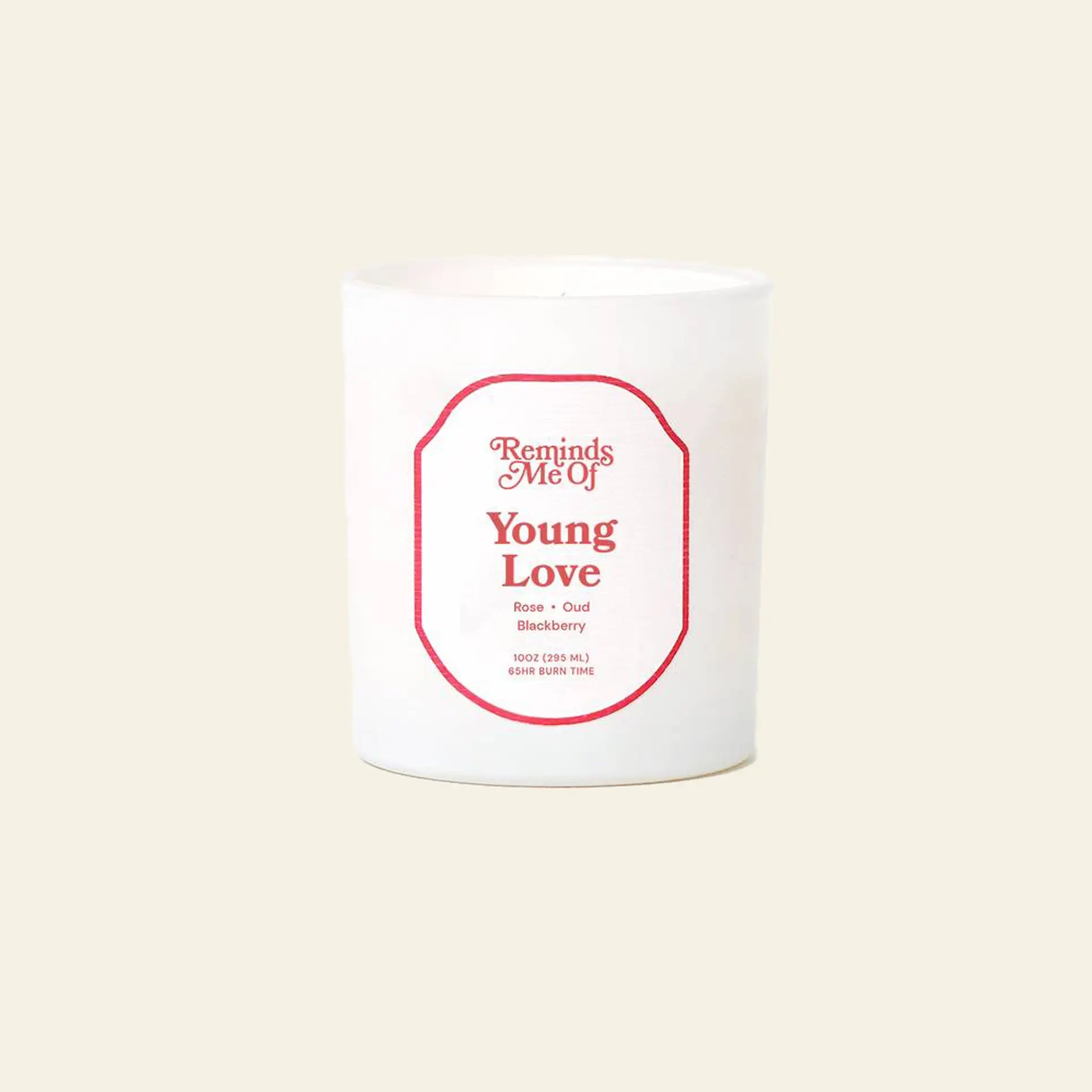 The Reminds Me Of Young Love Candle, 10oz by Reminds Me Of is a white candle in a glass jar with a red label. Scented with rose petals, oud, and blackberry. Light beige background and features the tagline Burn Every Time.