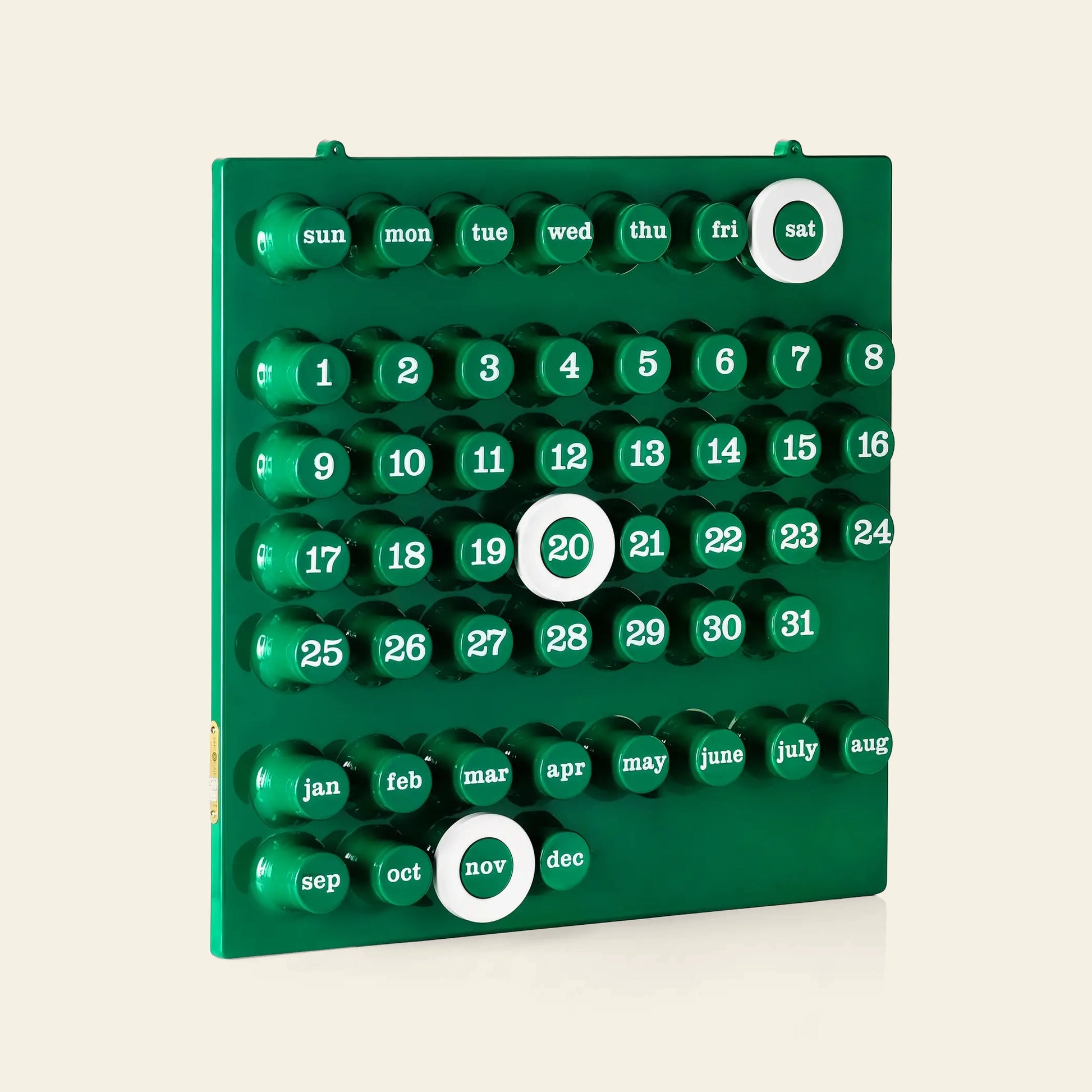 The Ring A Date Wall Calendar by Ring-A-Date is a green, minimalist wall calendar made in Italy from durable ABS plastic. Circular buttons mark days, dates, and months; Saturday the 20th and November are highlighted with white rings.