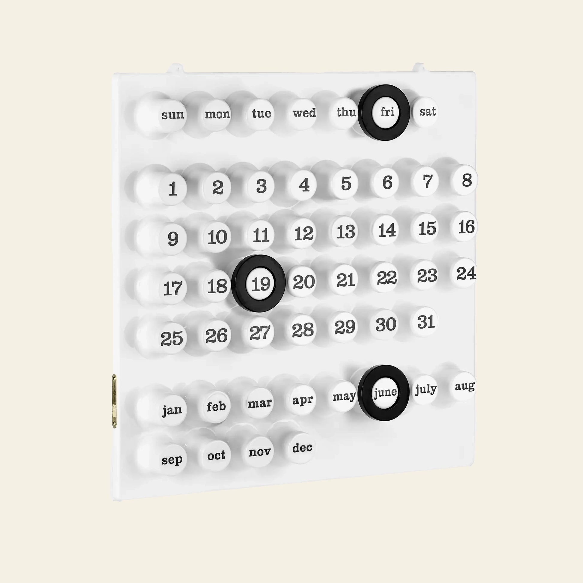 The Ring A Date Wall Calendar by Ring-A-Date is a modern, white Italian calendar with raised ABS plastic buttons for days, dates, and months. Black rings highlight Friday the 19th and June on a minimalistic layout with a plain light background.