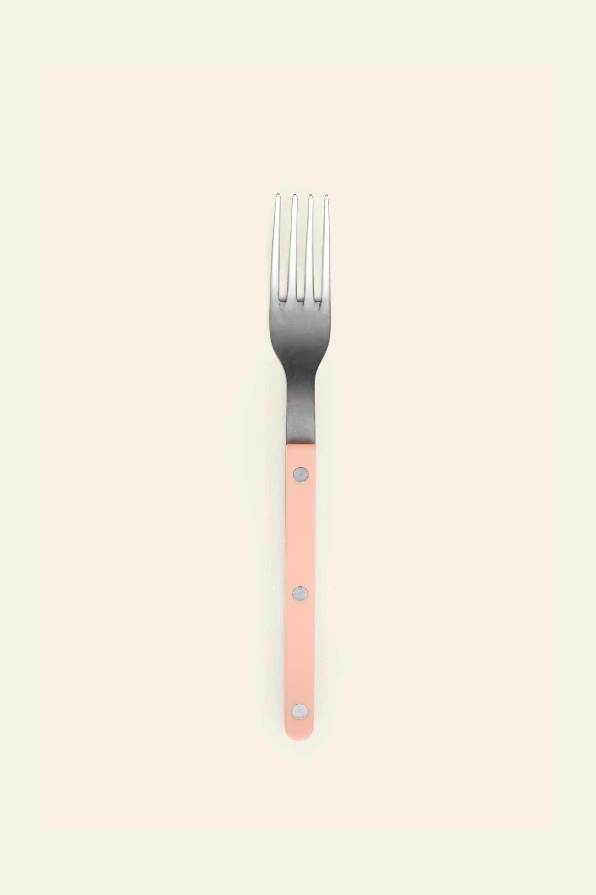 The Sabre Bistrot Vintage Dinner Fork by Sabre features a light pink handle with three silver rivets and a stainless steel head, displayed on a plain light beige background.