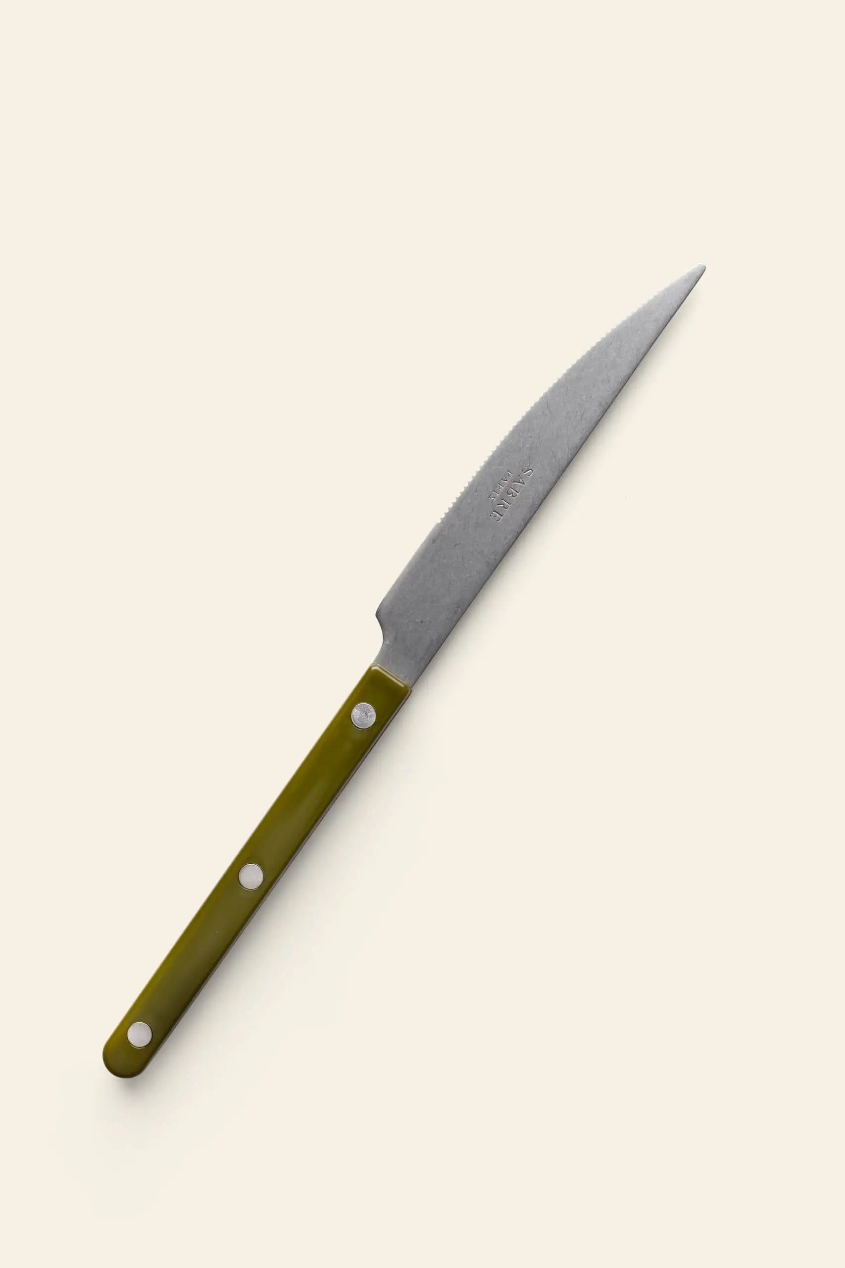 The Sabre Bistrot Vintage Dinner Knife by Sabre features a pointed blade and an olive green handle with three rivets, shown on a light background. Ideal as a rustic French-style dinner knife to enhance any table setting.