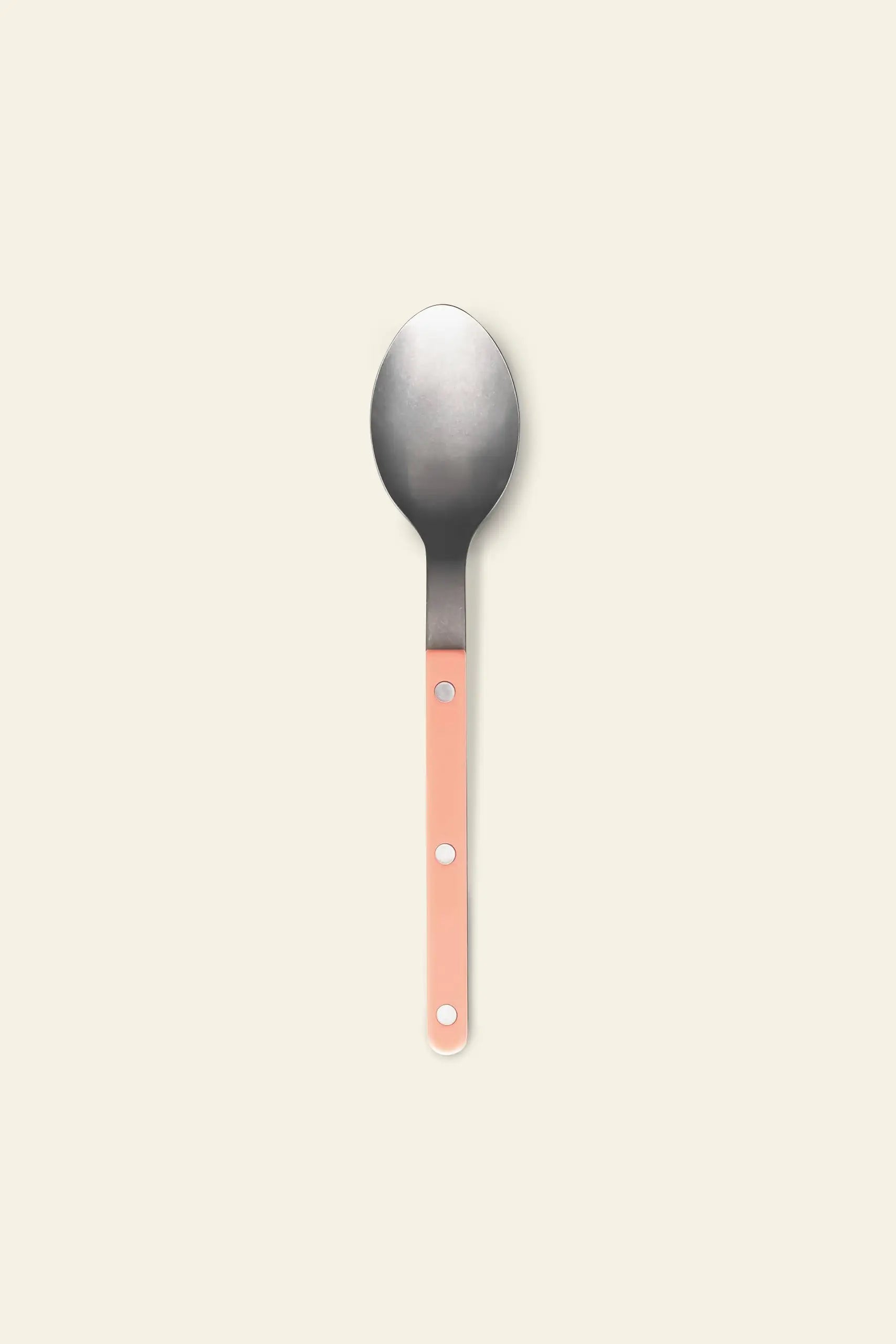 The Sabre Bistrot Vintage Soup Spoon by Sabre features a wide, round stainless steel bowl and a peach handle with two silver rivets, shown on an off-white background—ideal for adding French cafe charm to your table.