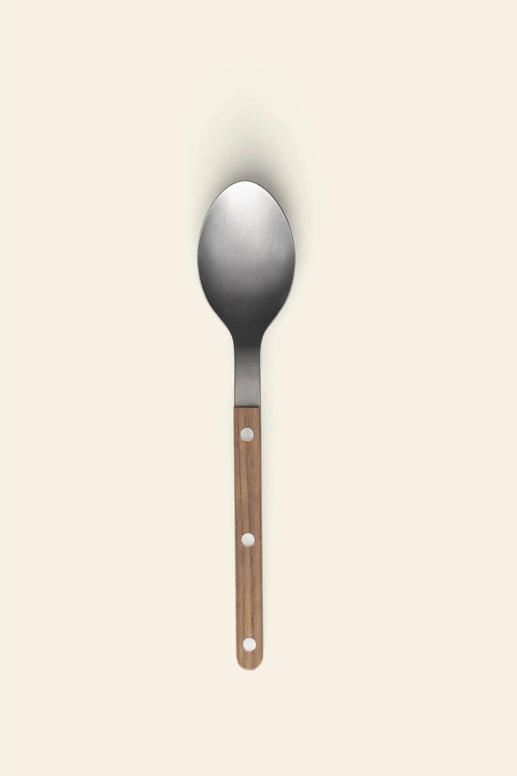 The Sabre Bistrot Vintage Soup Spoon by Sabre features a wooden handle with three circular holes and a stainless steel head, standing upright on a light beige background.