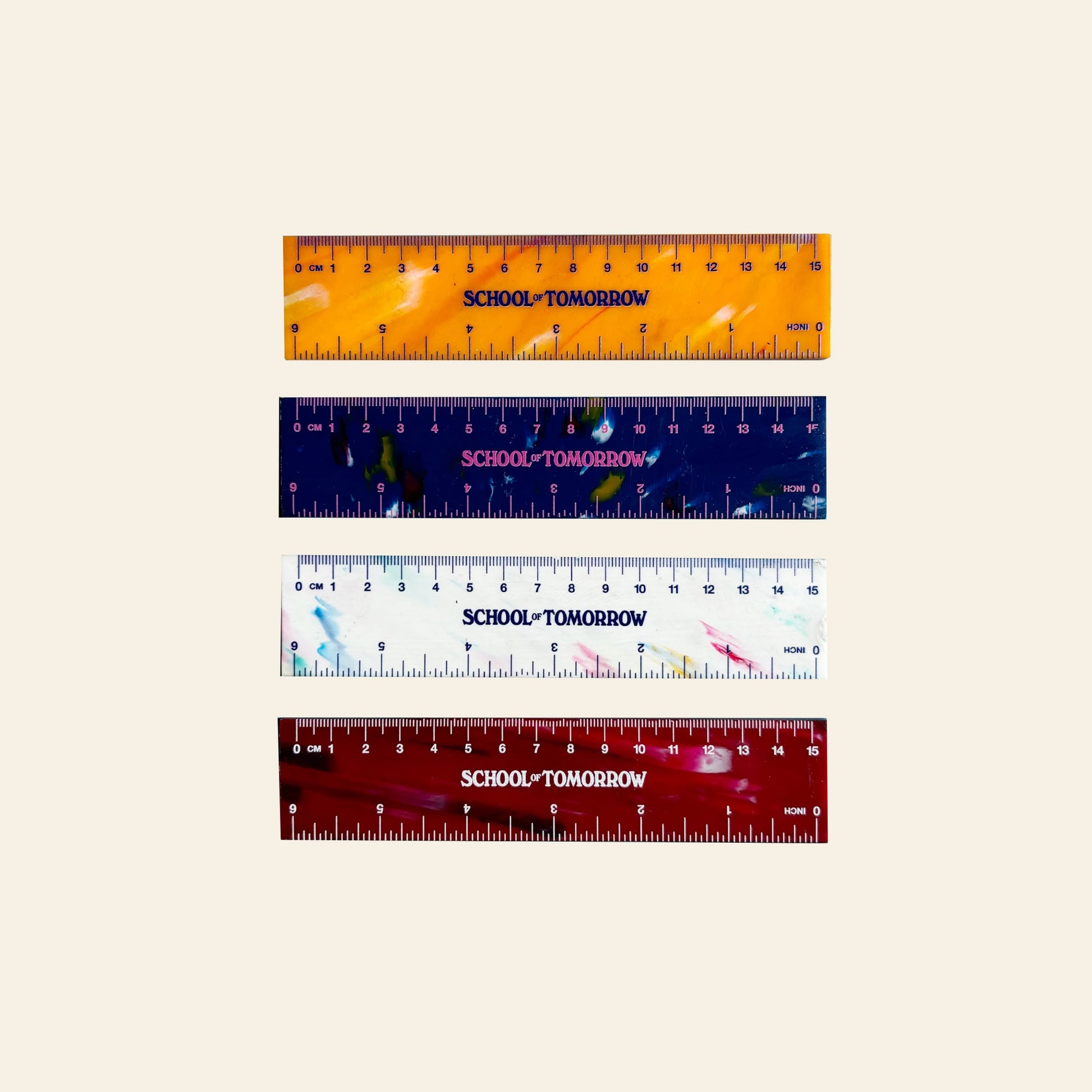 Four School of Tomorrow 15cm rulers by School of Tomorrow, in orange, dark blue, white, and red with unique patterns, are displayed horizontally on a beige background. Each is sustainably crafted and labeled SCHOOL TOMORROW.