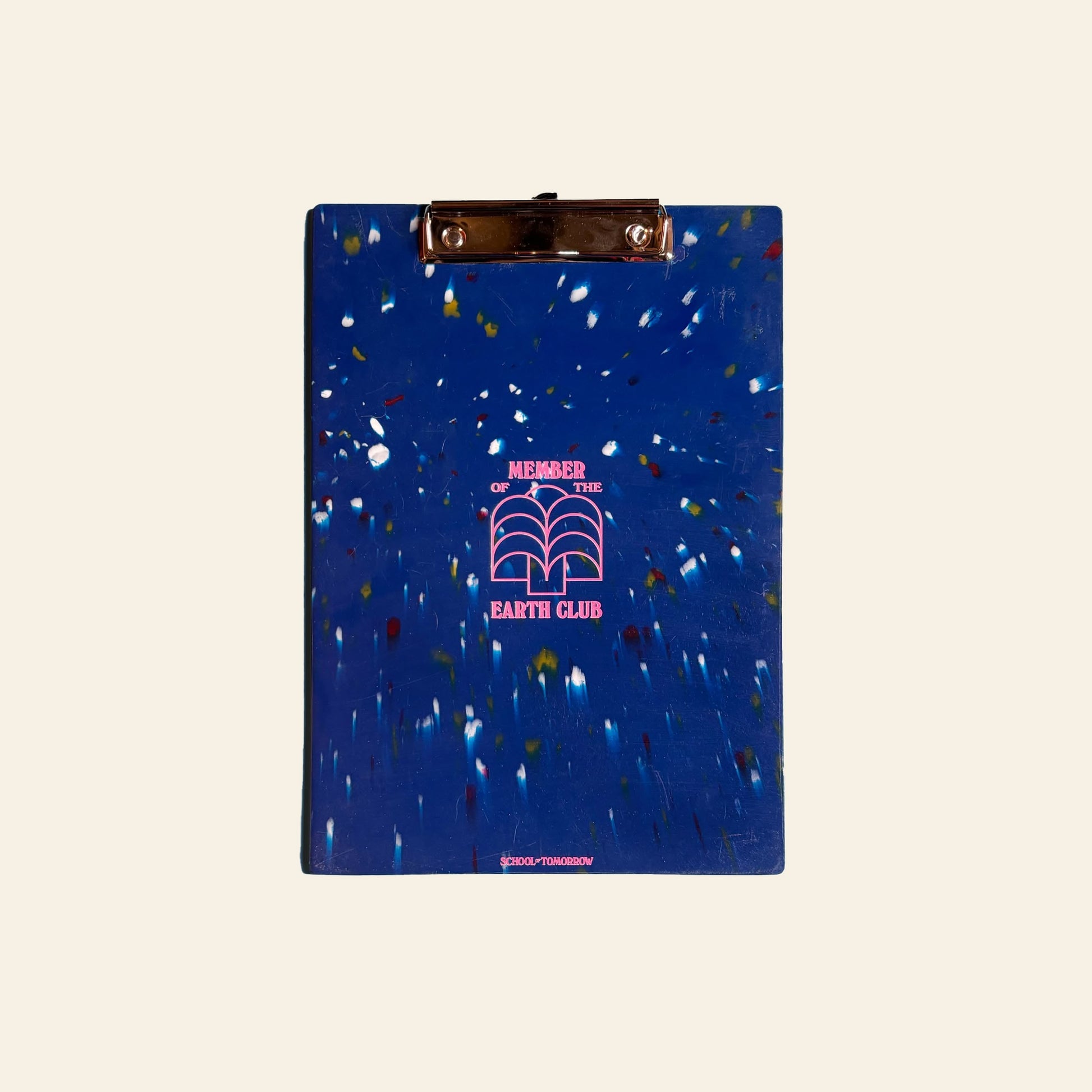 The School of Tomorrow A4 Clipboard in blue features colorful paint splatters, a metal clip, and MEMBER OF THE EARTH CLUB above an open book graphic, all printed in pink. Made from recycled bottle caps for sustainability.