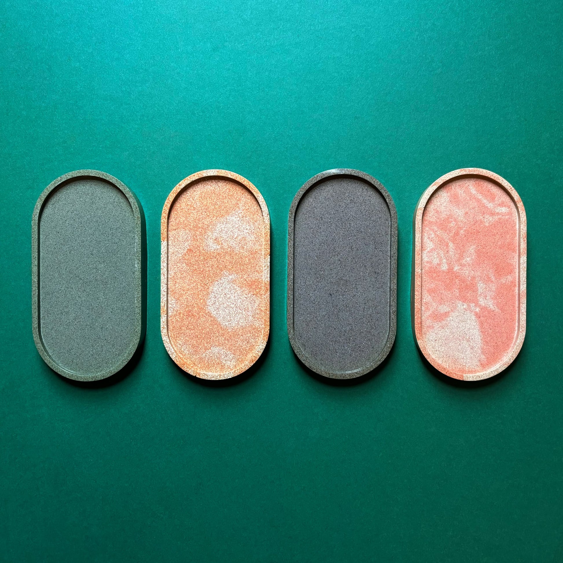 Four oval makeup pans in green, gold, dark gray, and peach rest in a School of Tomorrow All-Purpose Tray by School of Tomorrow, crafted from eggshell waste and displayed against a teal background.