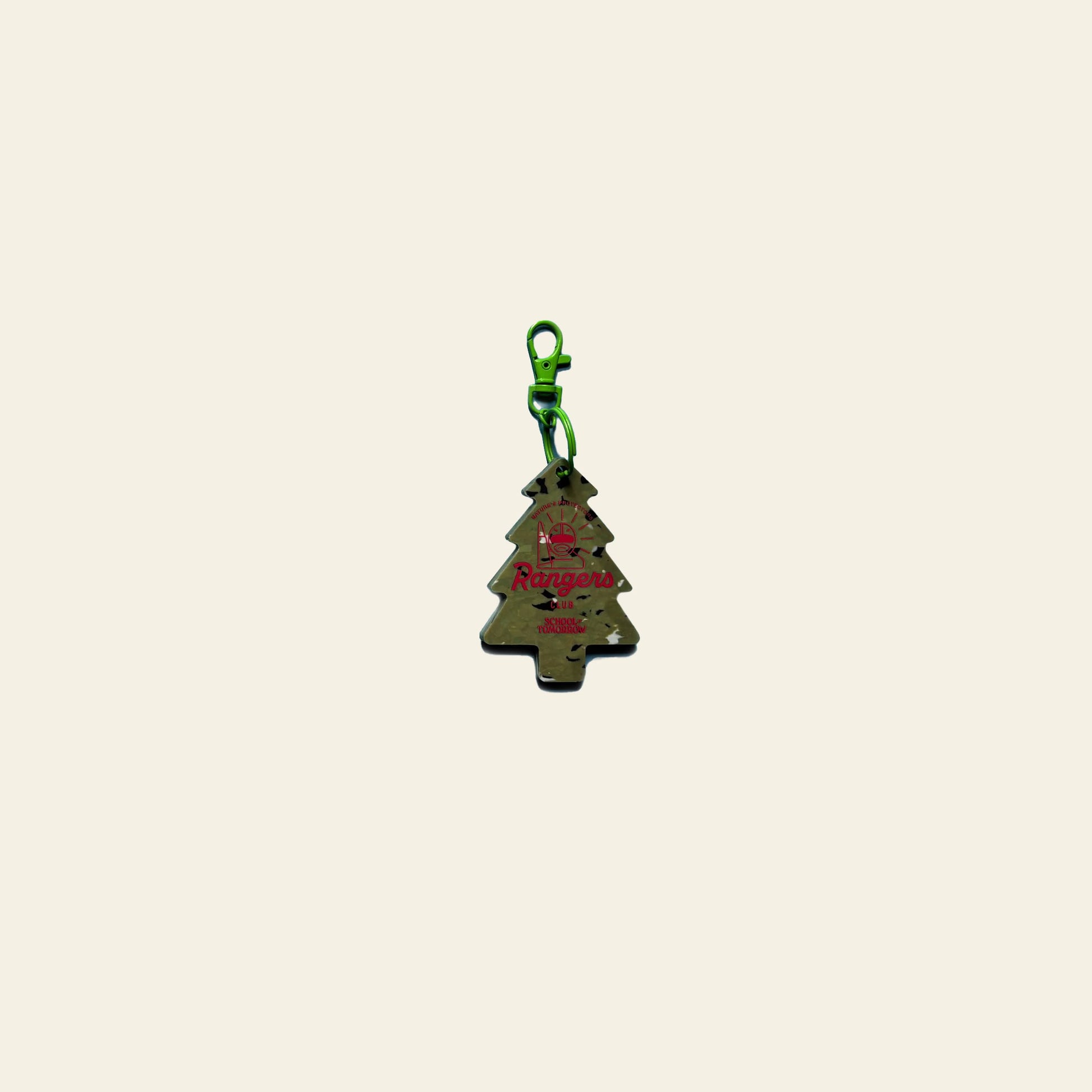 The School of Tomorrow Keychain - Green by School of Tomorrow, shaped like a metallic Christmas tree with a green clasp and red Rangers text, rests on an off-white background—perfect for fans of festive handmade accessories.