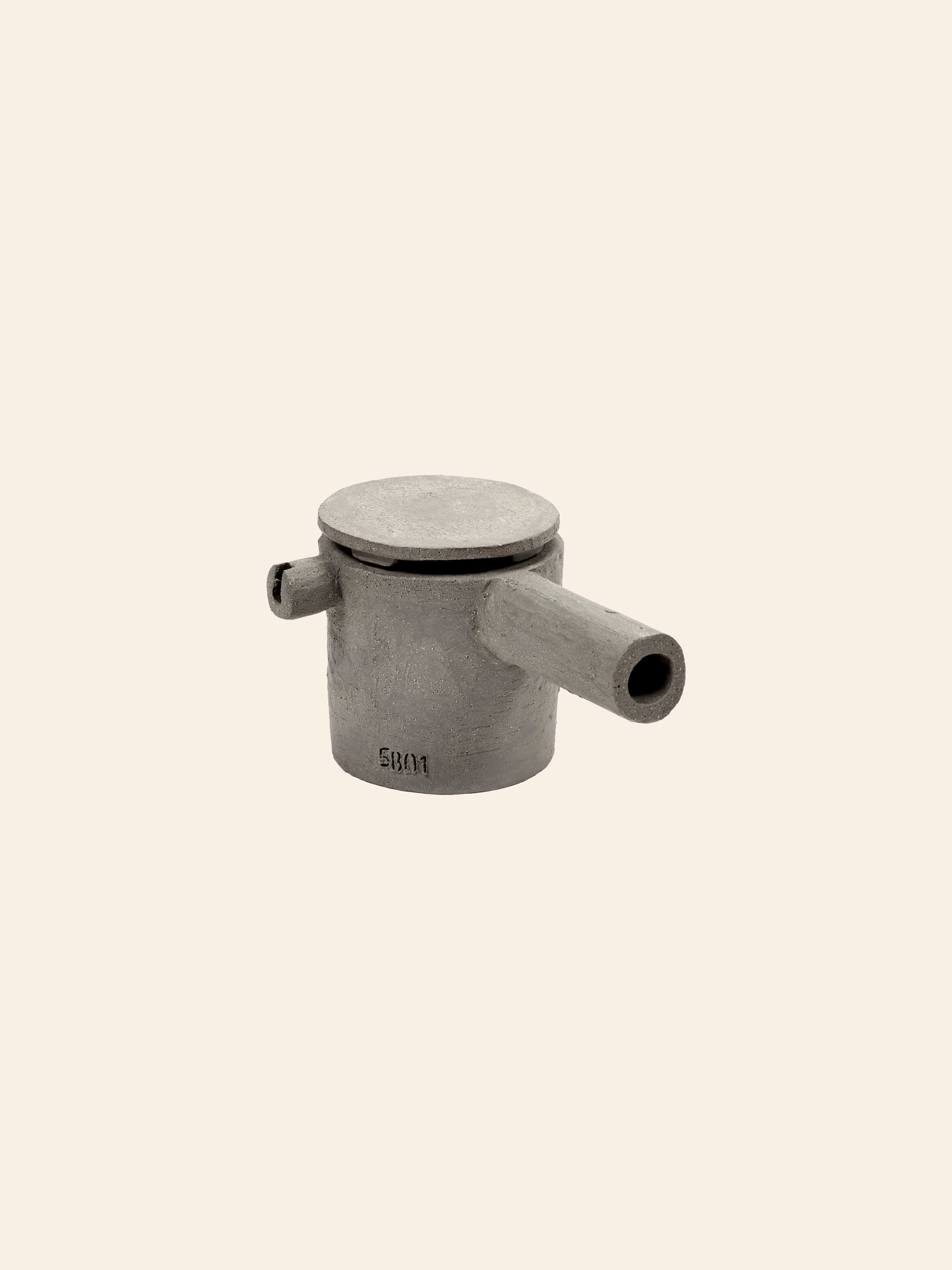 The Serax Fck Teapot N°3 - Grey Brown by Serax is a minimalist teapot with a cylindrical shape, flat lid, short spout, and side handle in a concrete-like finish, shown against a plain beige background.
